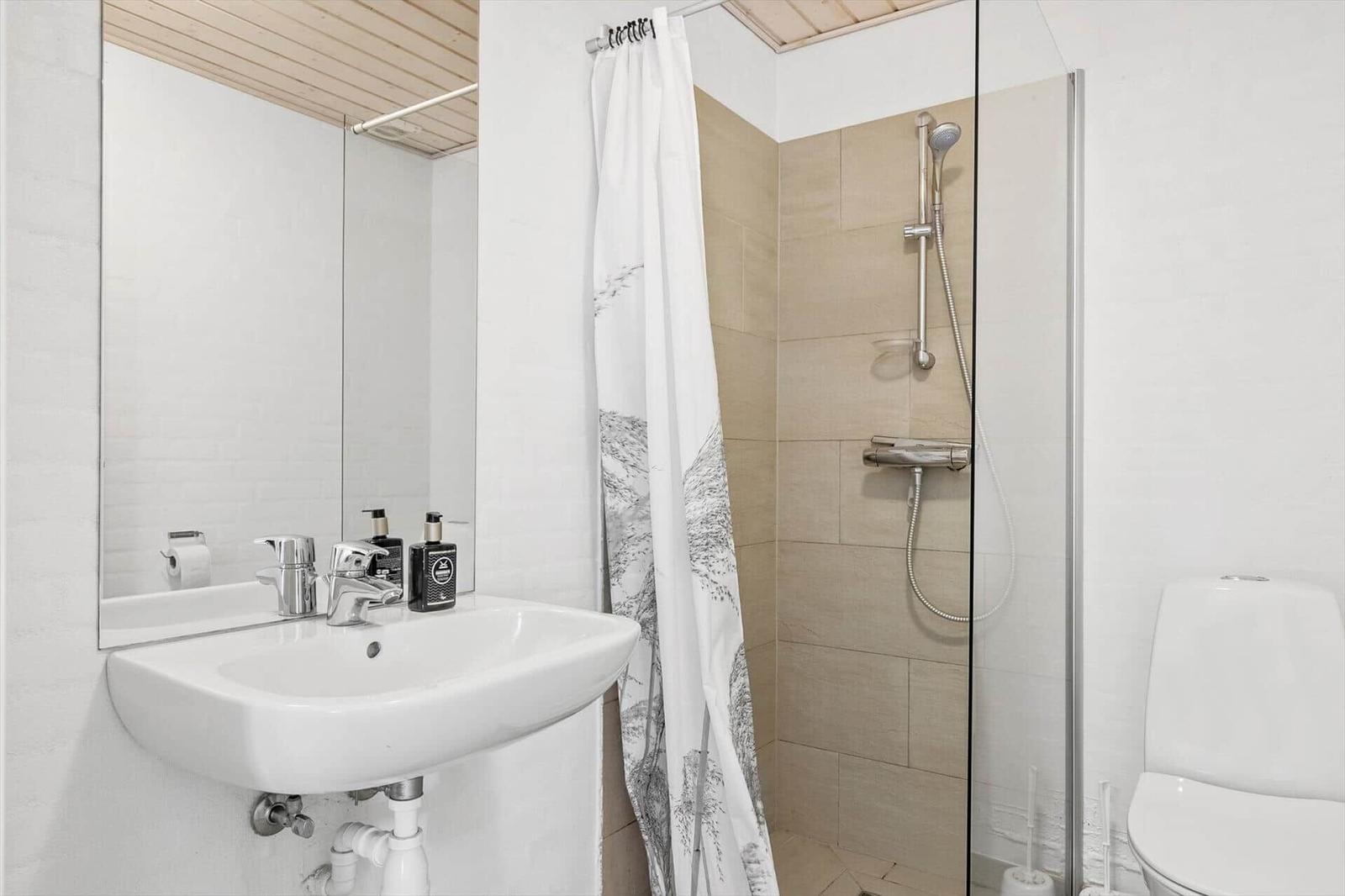 Badezimmer mit Dusche, Waschbecken und Toilette.