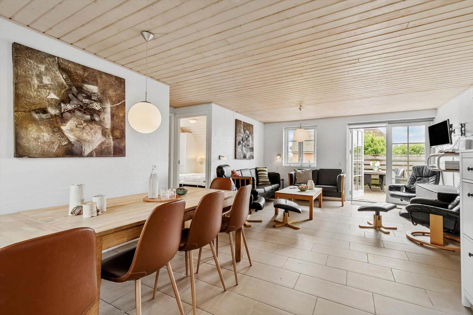 Wohn- und Essbereich mit Holzdecke, Tisch, Stühle und Sofa.