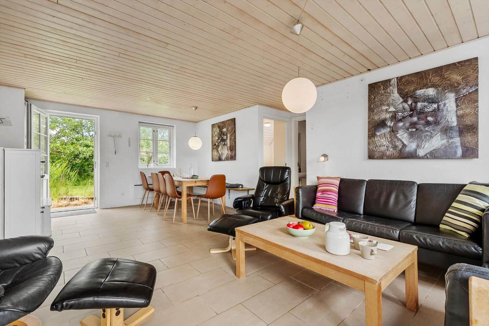Wohn- und Essbereich mit Ledersofa, Holztisch und Blick auf den Garten.