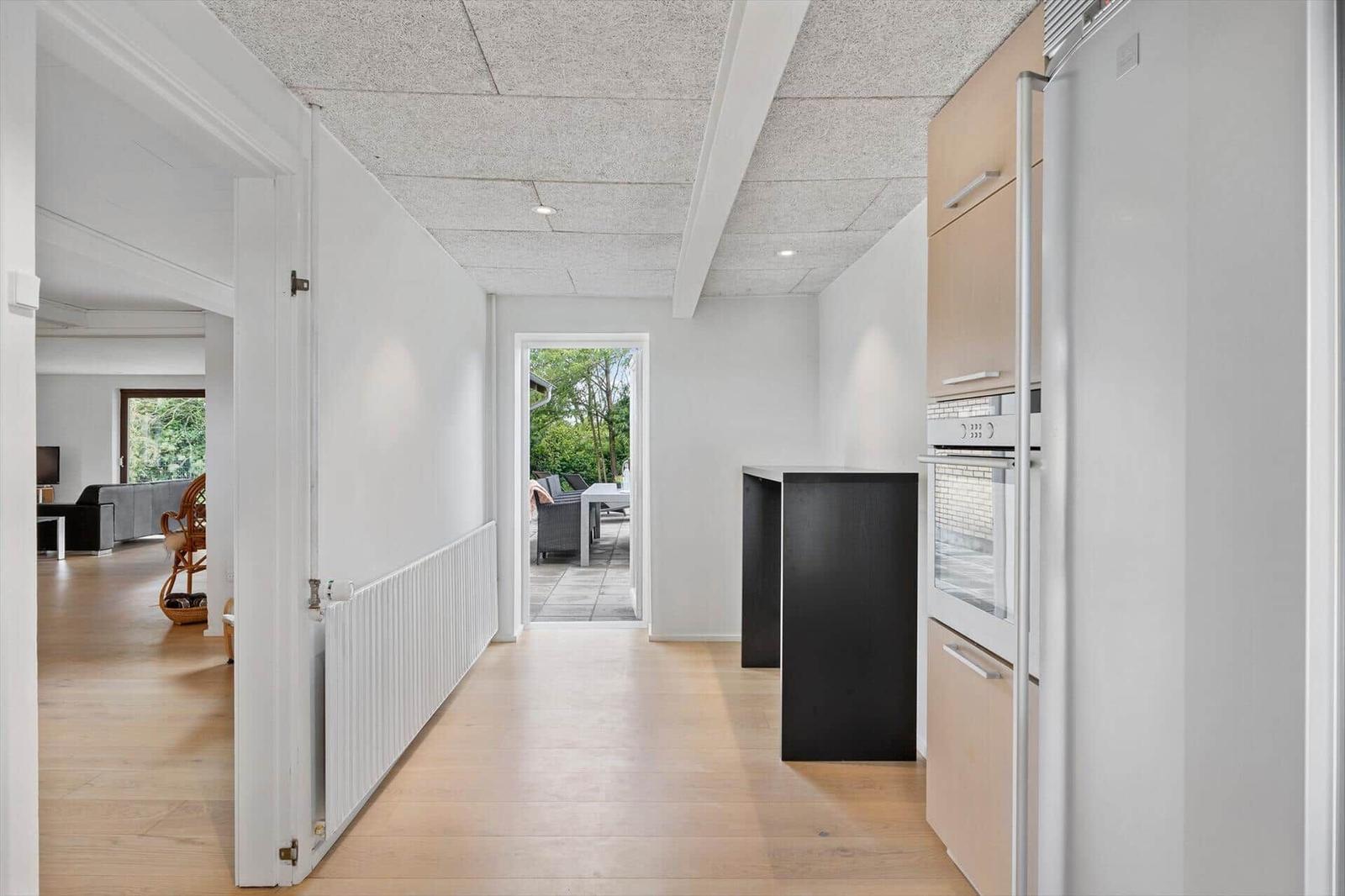 Kitchen with wooden floor and view to terrace. Living area and garden are visible.