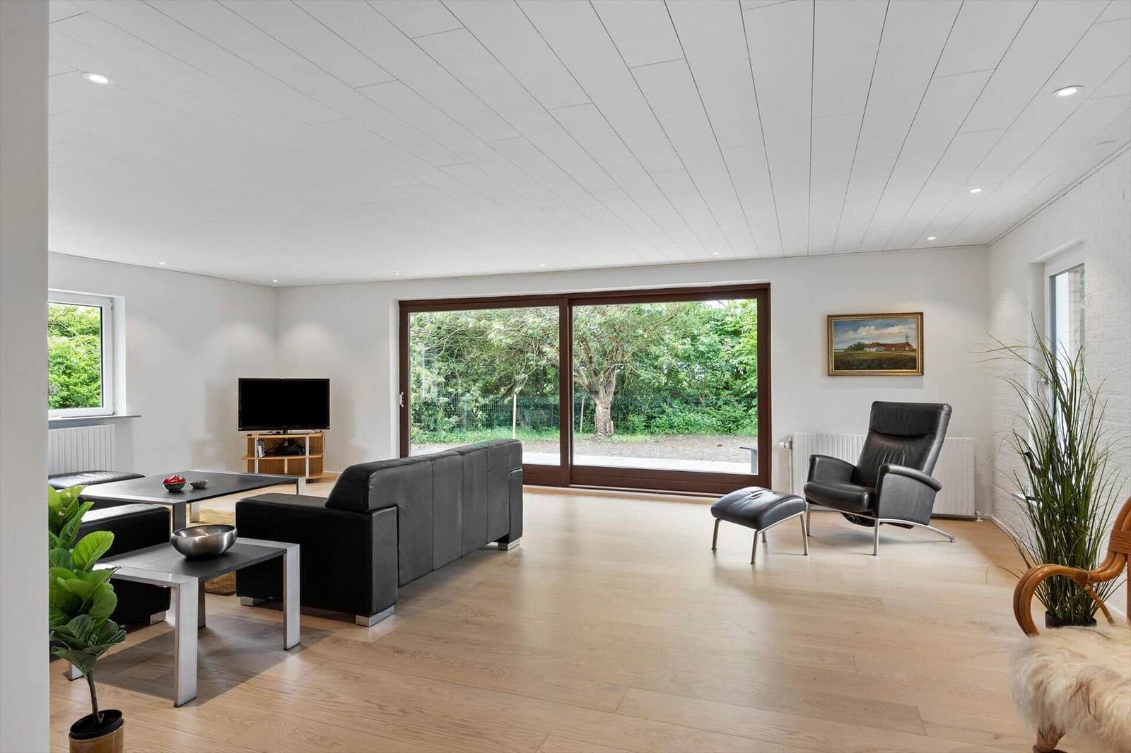 Living room with sofa, armchair, and view of green areas.