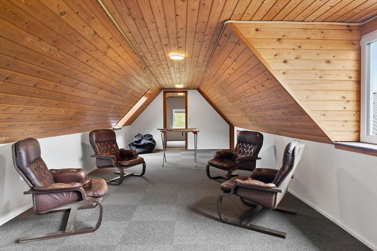 Attic room with four leather chairs and wooden ceiling