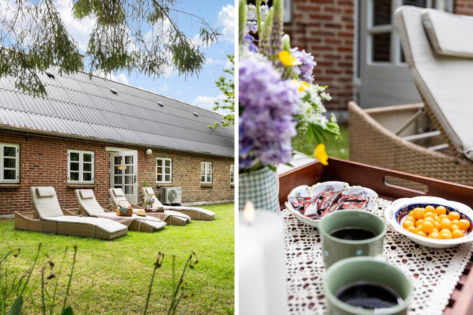 Haus mit Garten, Liegen und Blumen. Tisch mit Kaffee, Obst und Schokolade.