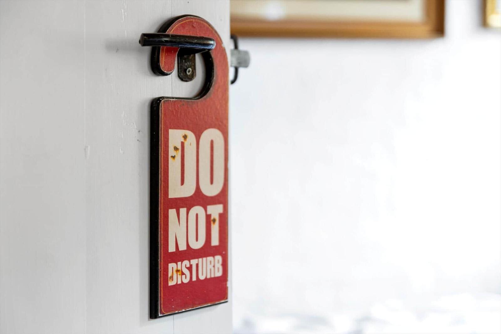 Rotes Do Not Disturb-Schild an einer Tür mit Metallgriff.