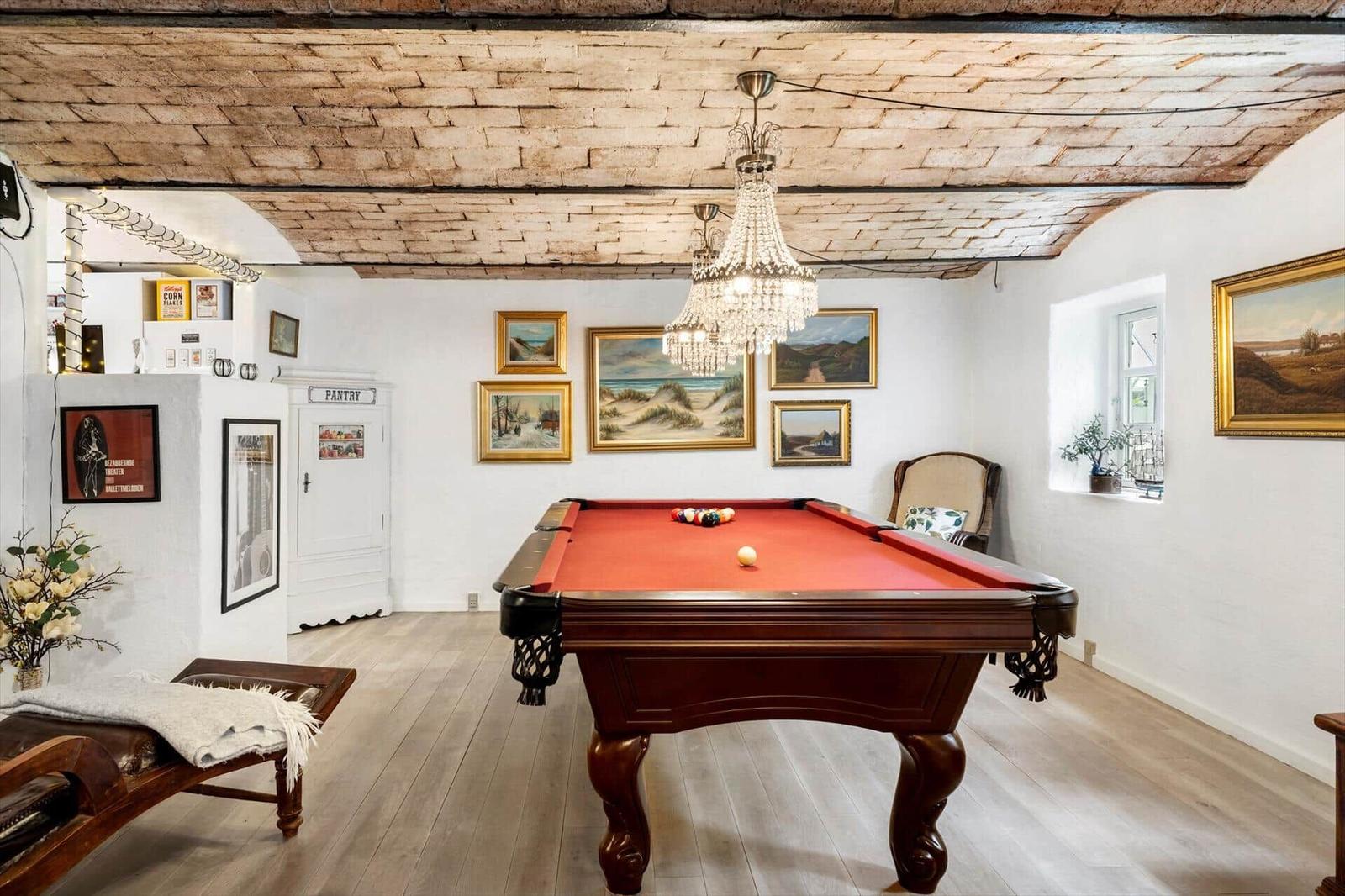 Raum mit Billardtisch, Holzboden und Deckenbalken. An den Wänden hängen Bilder.