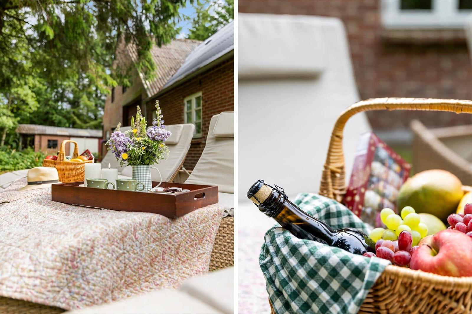 Außenbereich mit Liegestühlen, Blumen und Picknickkorb mit Obst und Flasche.