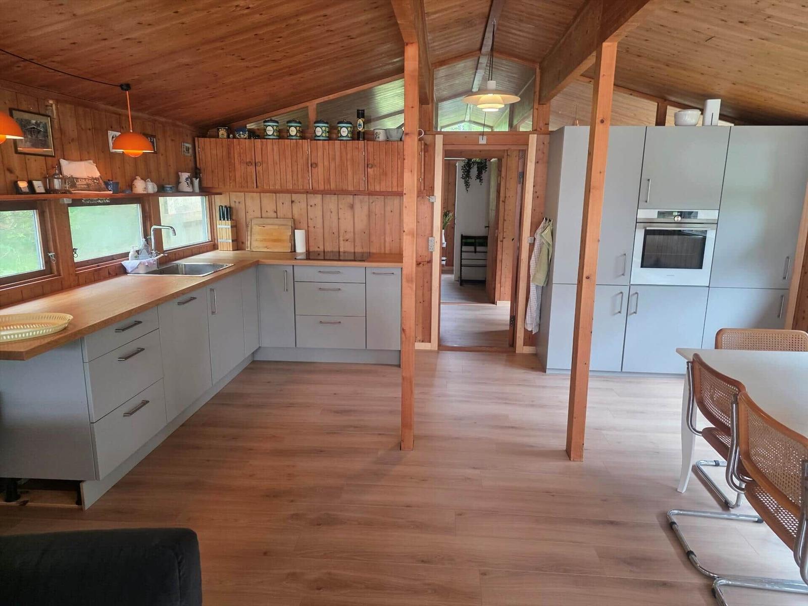 Küche mit Holzdecke, Arbeitsfläche und Einbauküche. Essbereich mit Tisch und Stühlen.