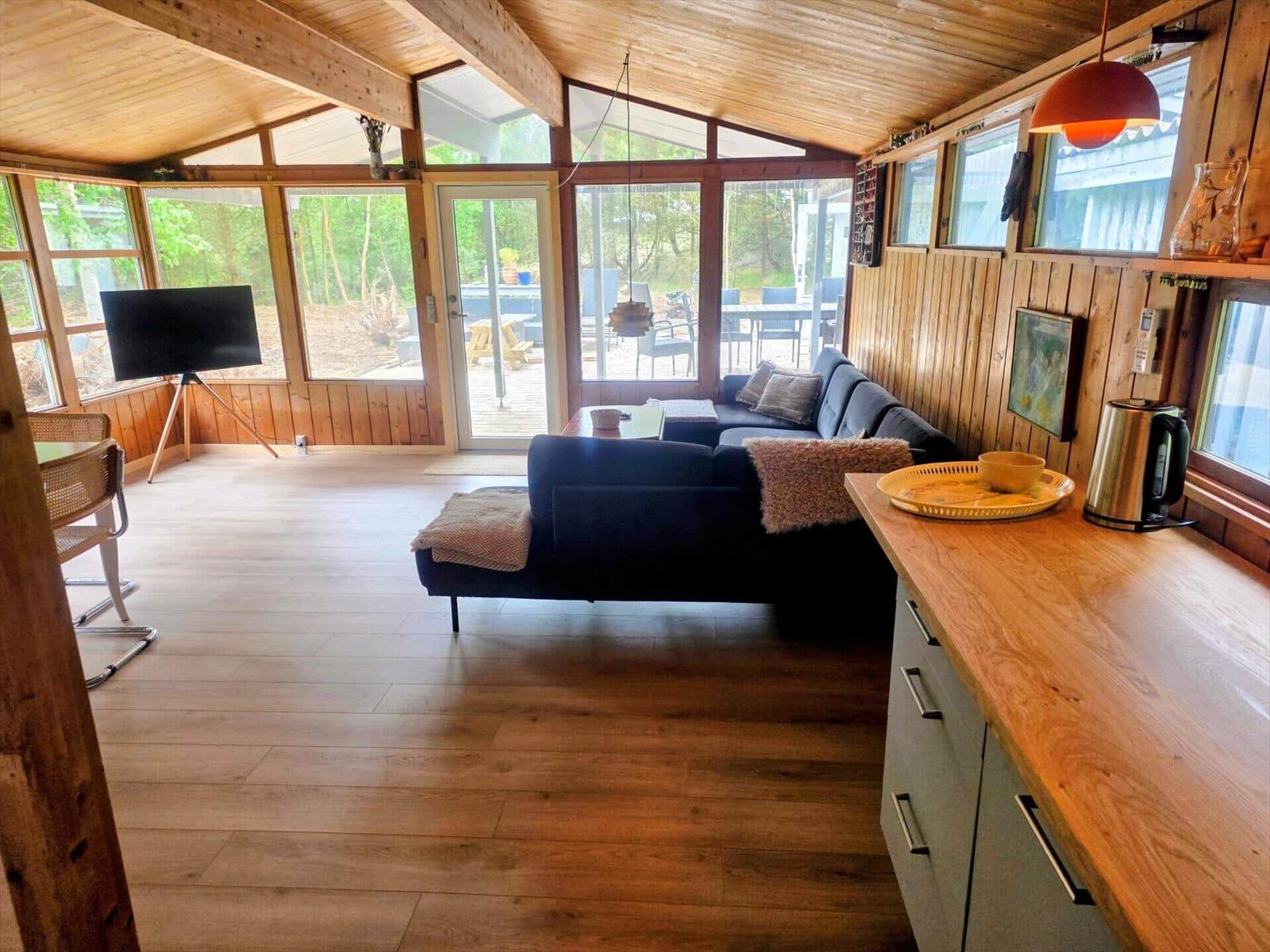 Wohn- und Essbereich mit Holzdecke, Sofa und Küchenzeile.