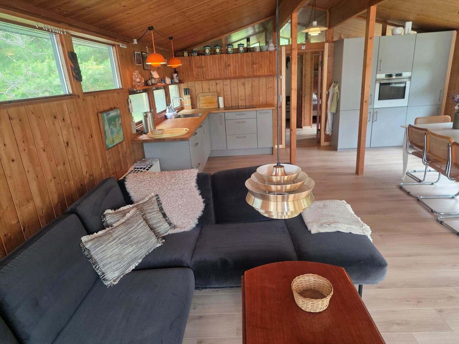 Wohnzimmer mit Sofa, Esstisch und Küche im Holzhaus