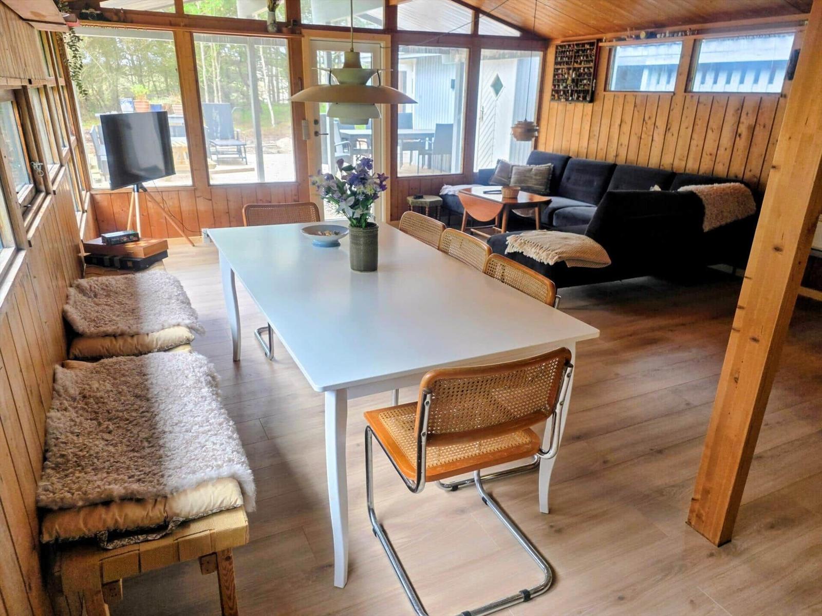 Essbereich mit weißem Tisch, Stühlen und Sofa. Holzwände und Boden.