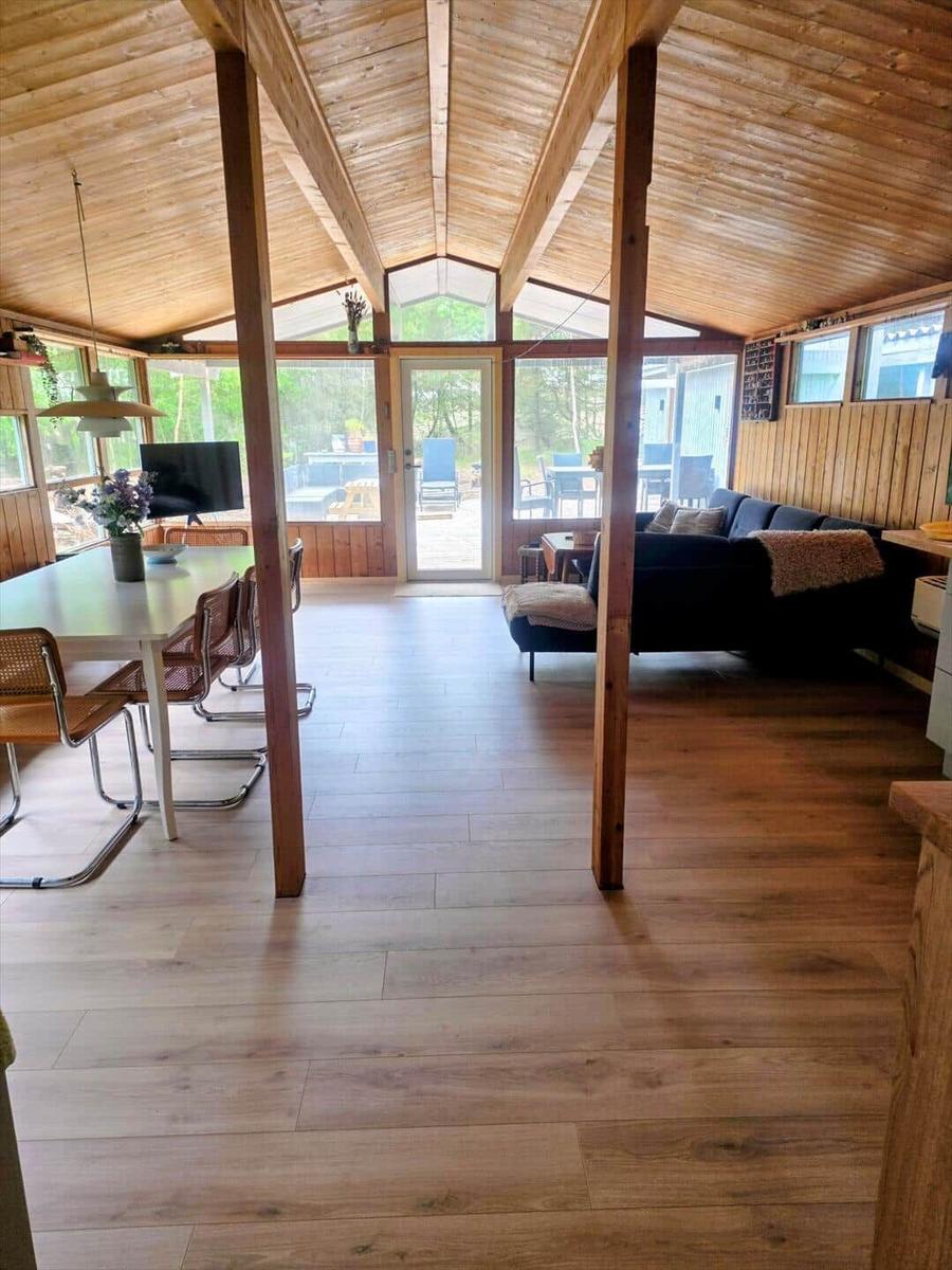 Haus mit Holzdecke, Essbereich und Wohnbereich mit Sofa und Blick auf Garten.