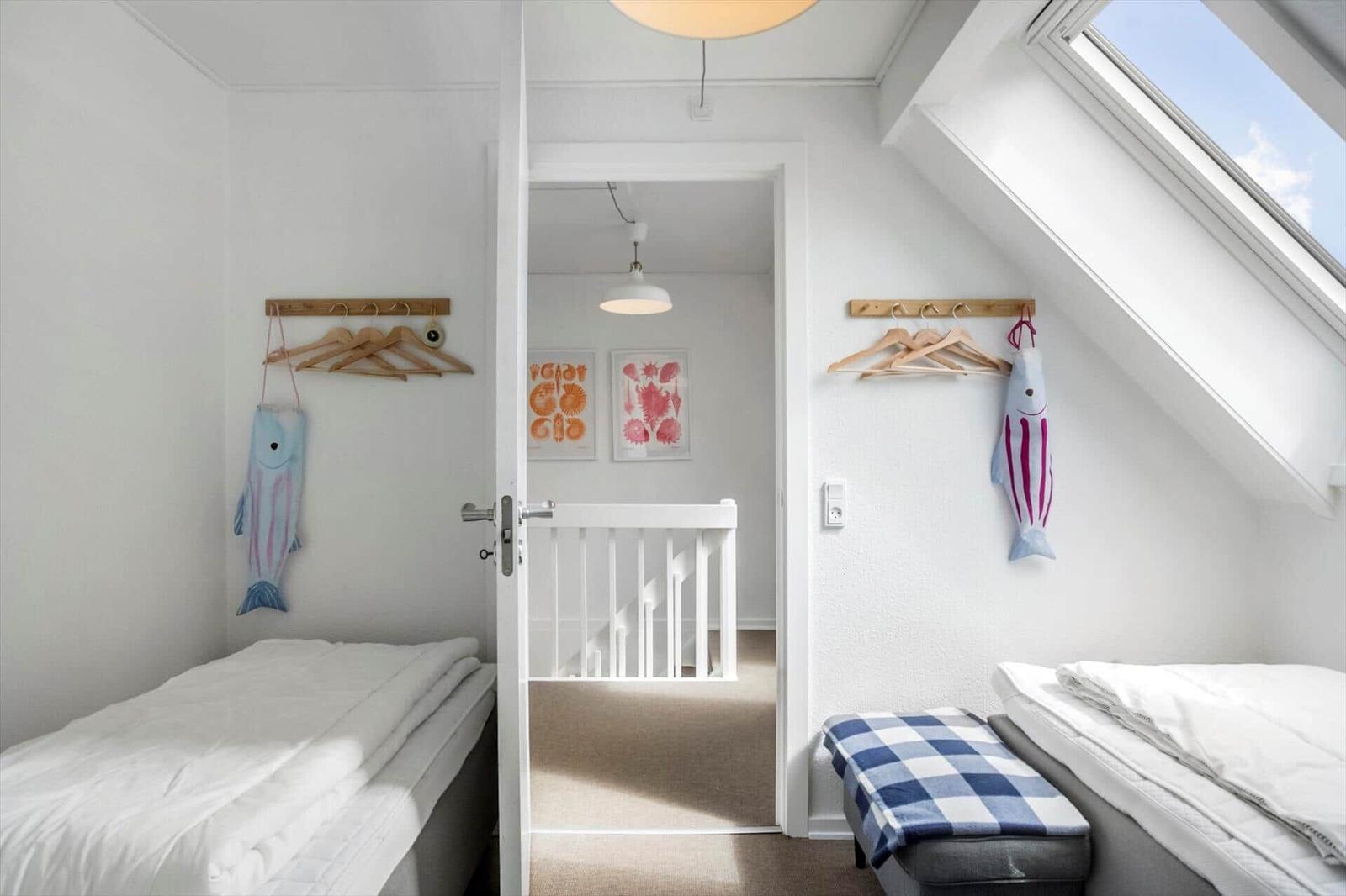 Zwei Schlafzimmer mit Dachschrägen, Kleiderhaken und Fischdekorationen.