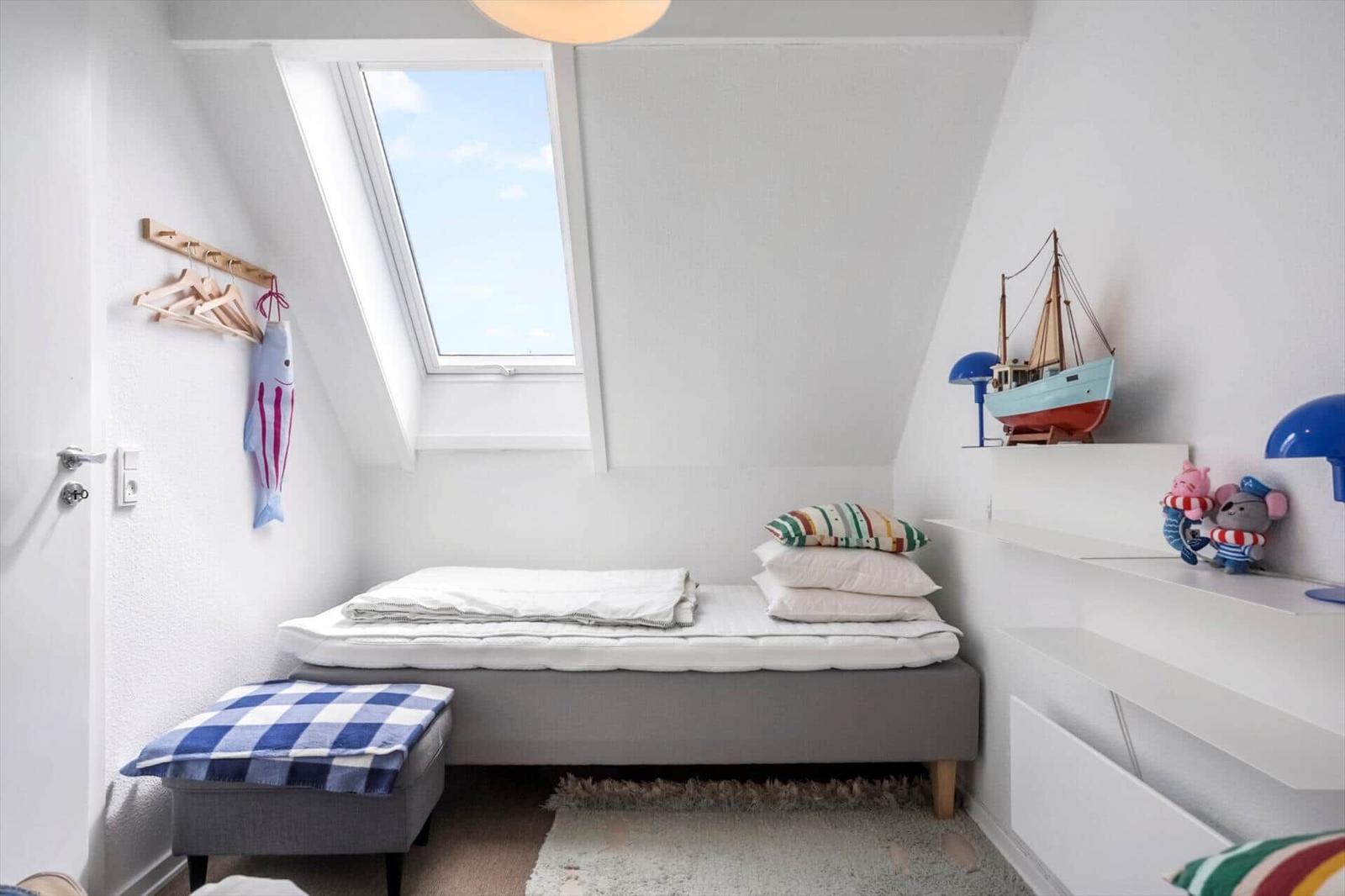 Ein Schlafzimmer mit Dachfenster, Bett, Kissen und Dekoration.