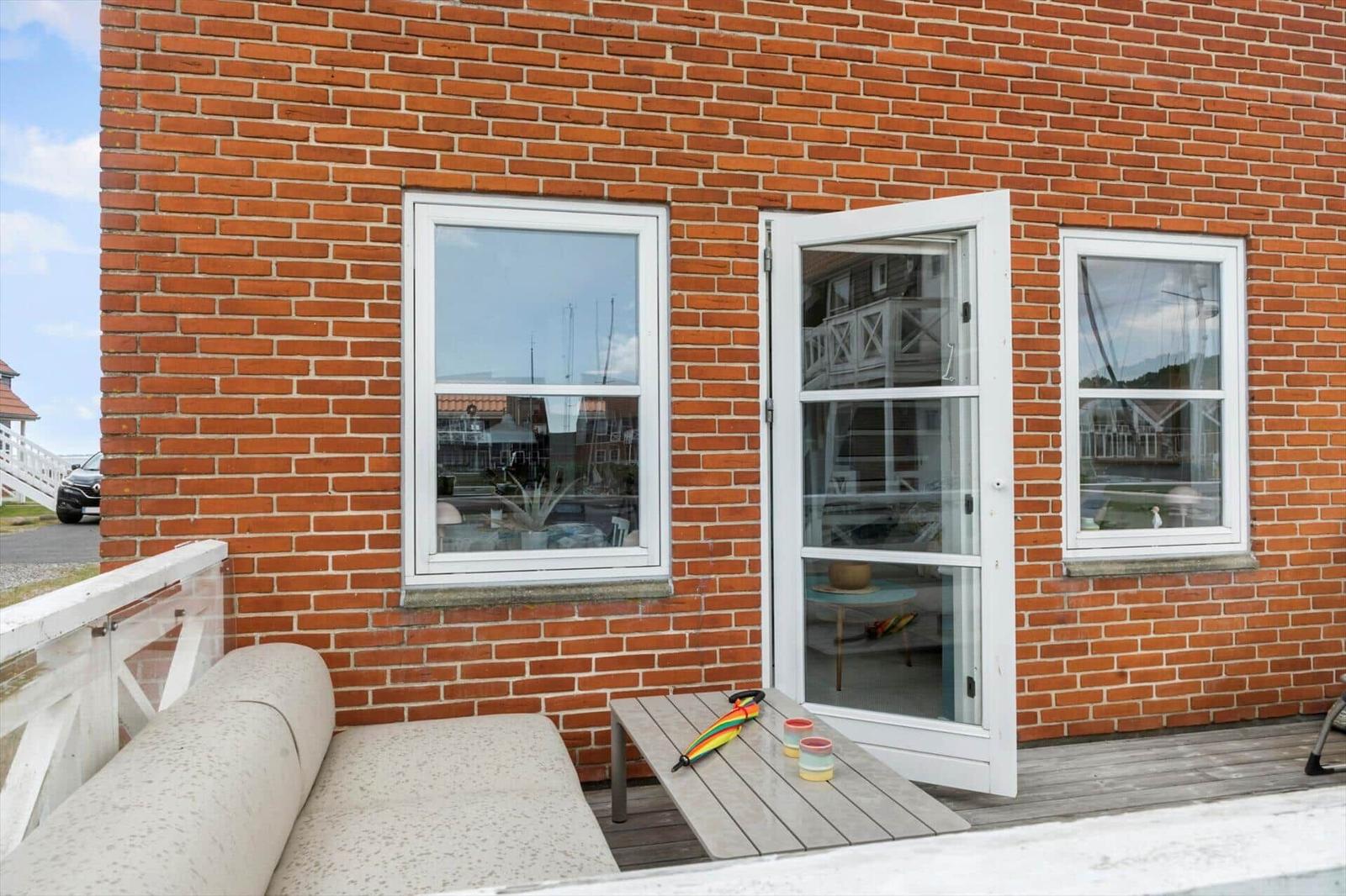 Roter Backsteinbau mit offener Tür und Terrasse mit Sofa und Tisch.