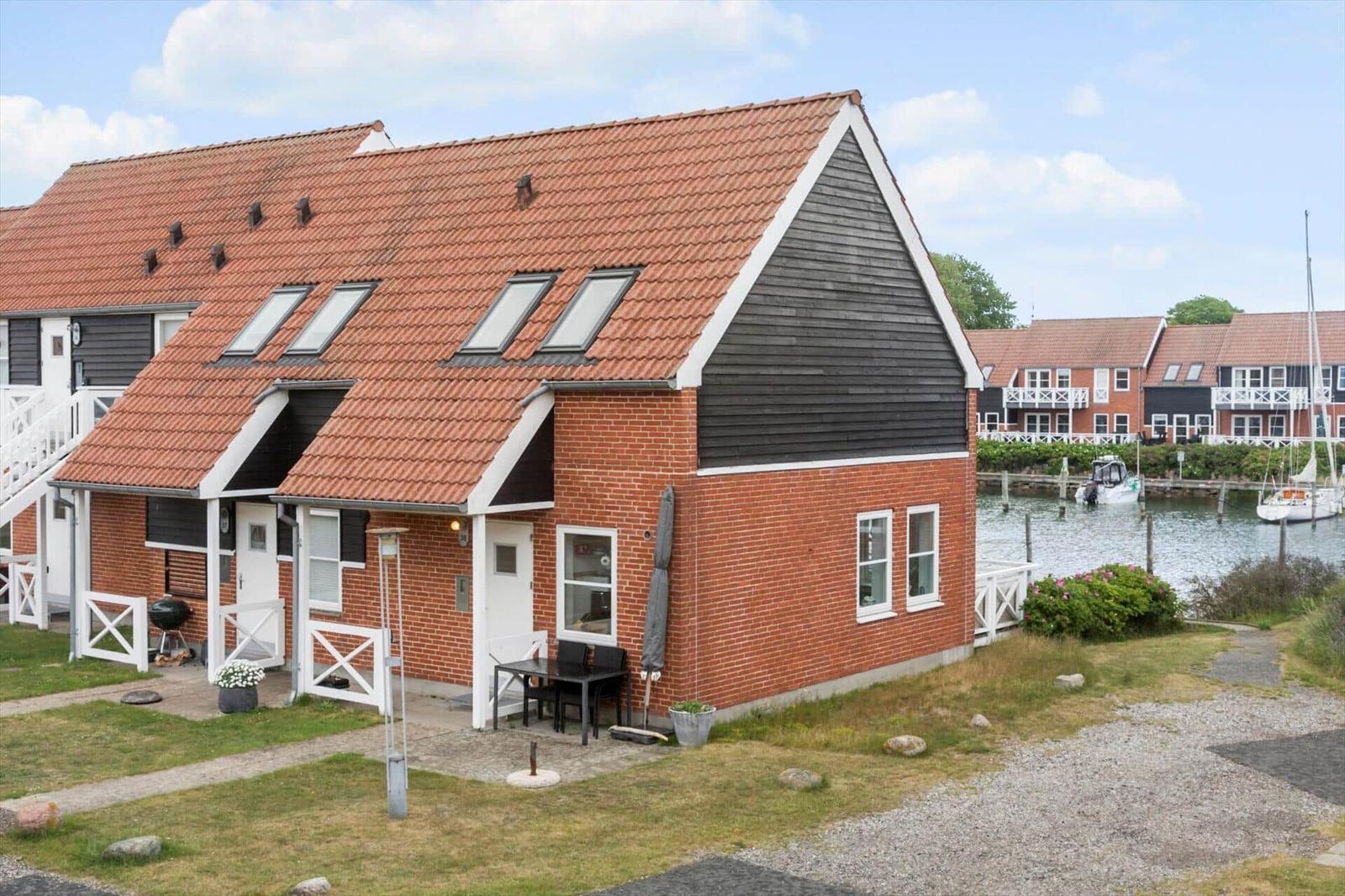 Haus mit rotem Dach und Backsteinfassade an Wasserfront mit Booten.