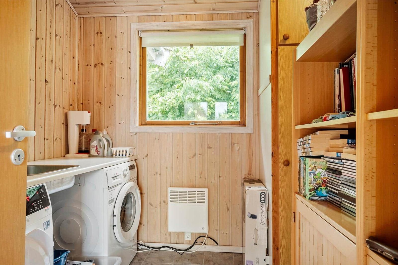 Waschraum mit Waschmaschine, Fenster und Bücherregal.