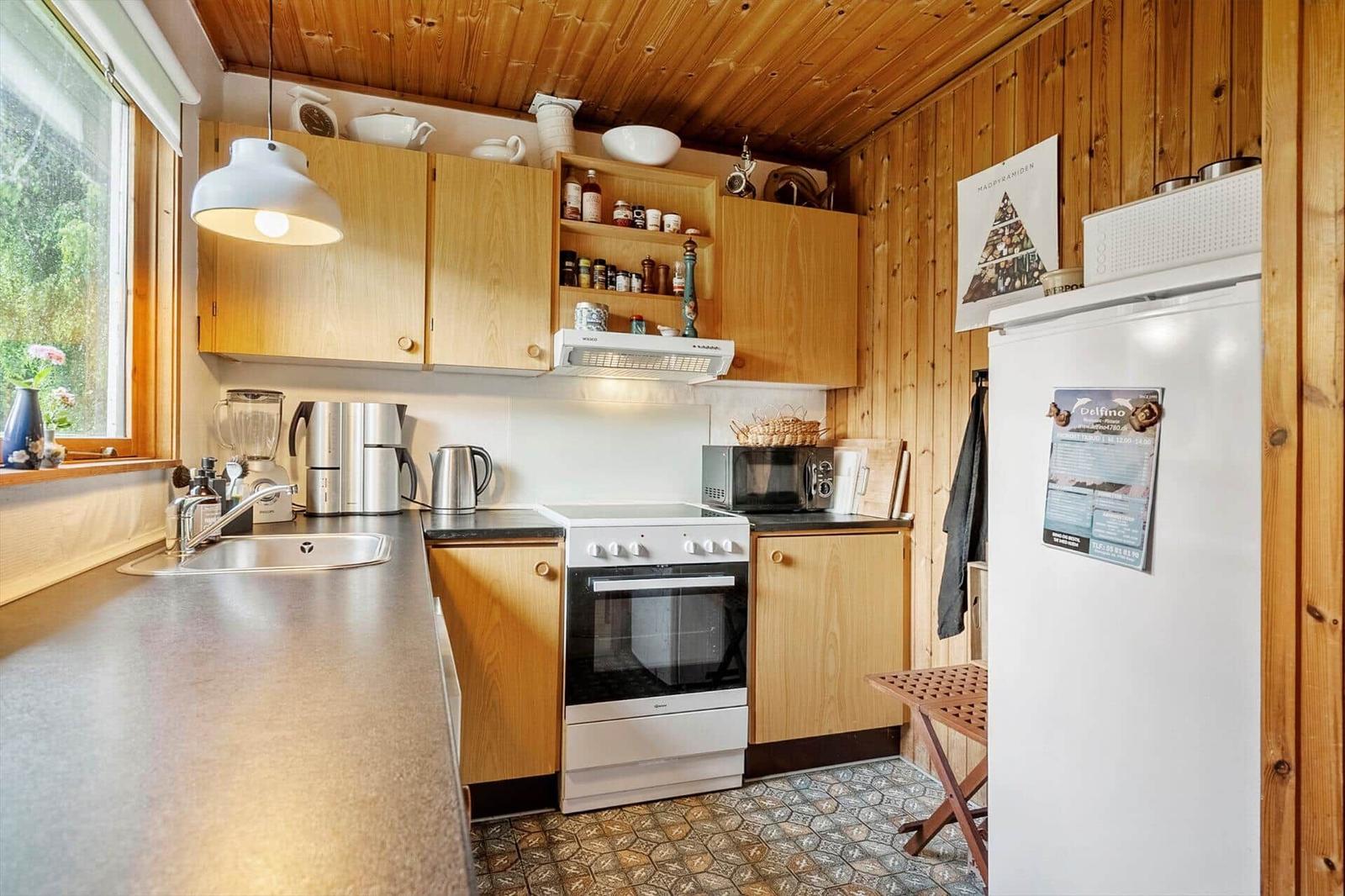 Küche mit Holzwand, Küchenschränken, Herd und Kühlschrank.