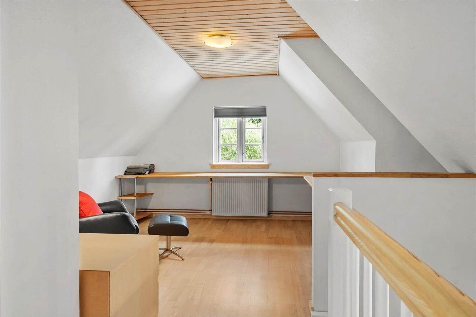Dachgeschosszimmer mit Holzboden, Fenster und Arbeitsplatz