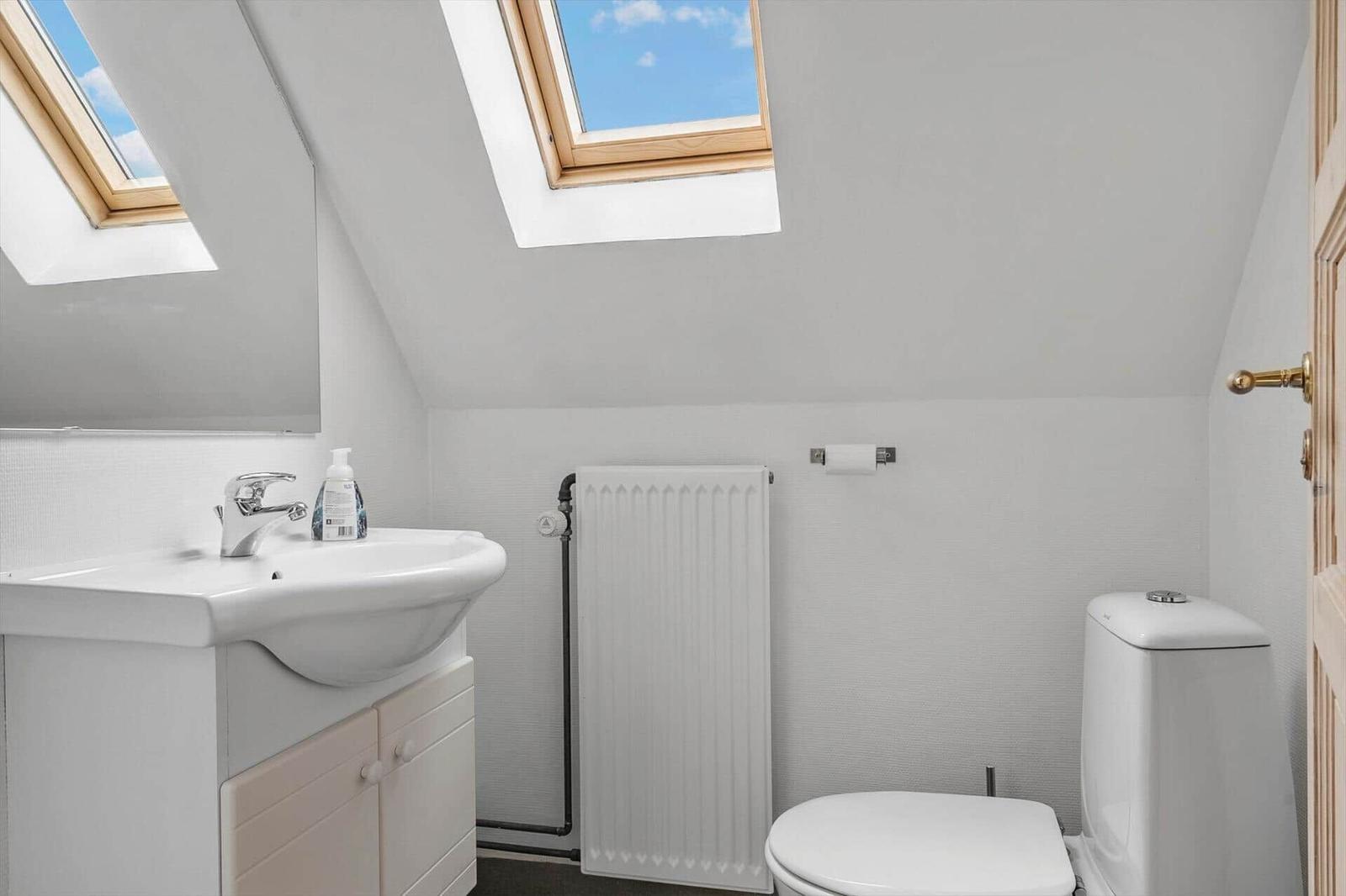 Badezimmer mit Waschbecken, Toilette und Dachfenstern