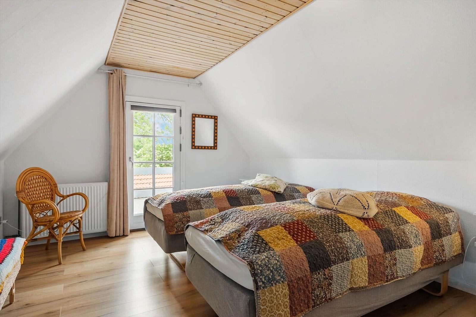 Zimmer mit Doppelbett, Holzdecke und Fenster zur Aussicht.