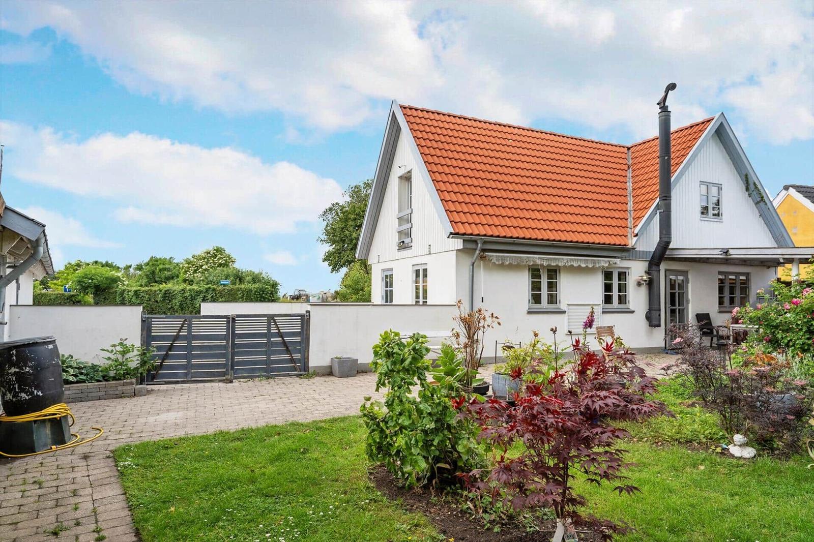 Ein weißes Haus mit rotem Dach, Garten und Terrasse.