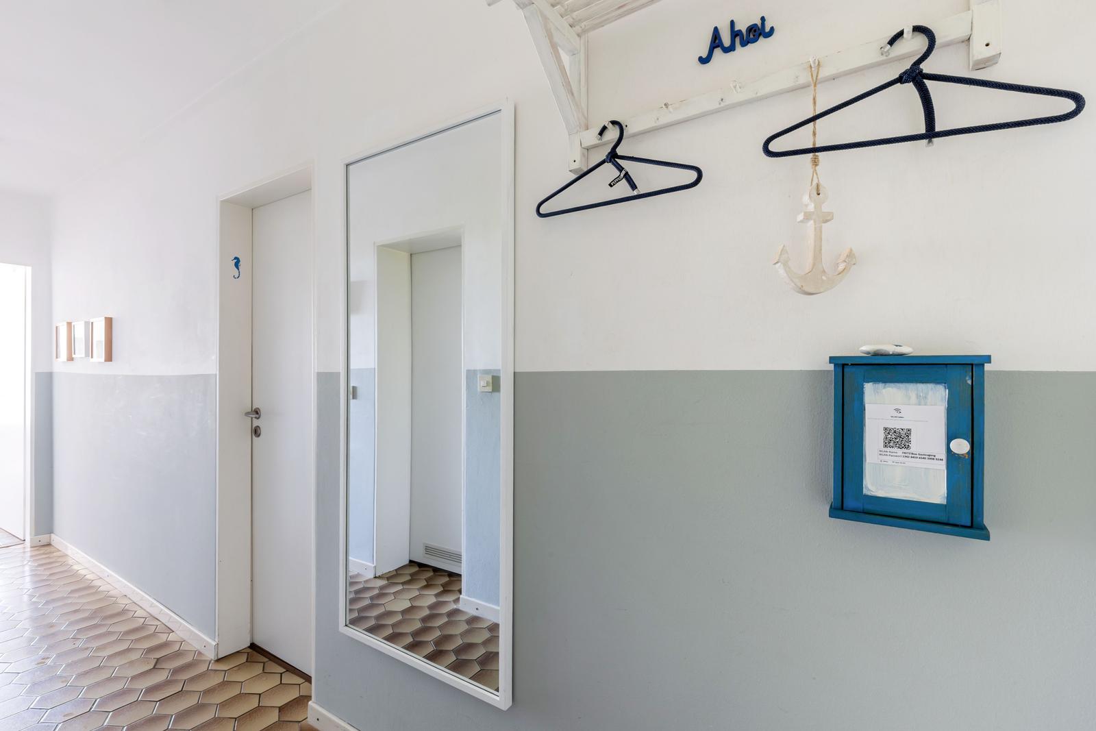 Flur mit Spiegel, Kleiderhaken und blauem Schrank. Wandfarbe weiß und grau.