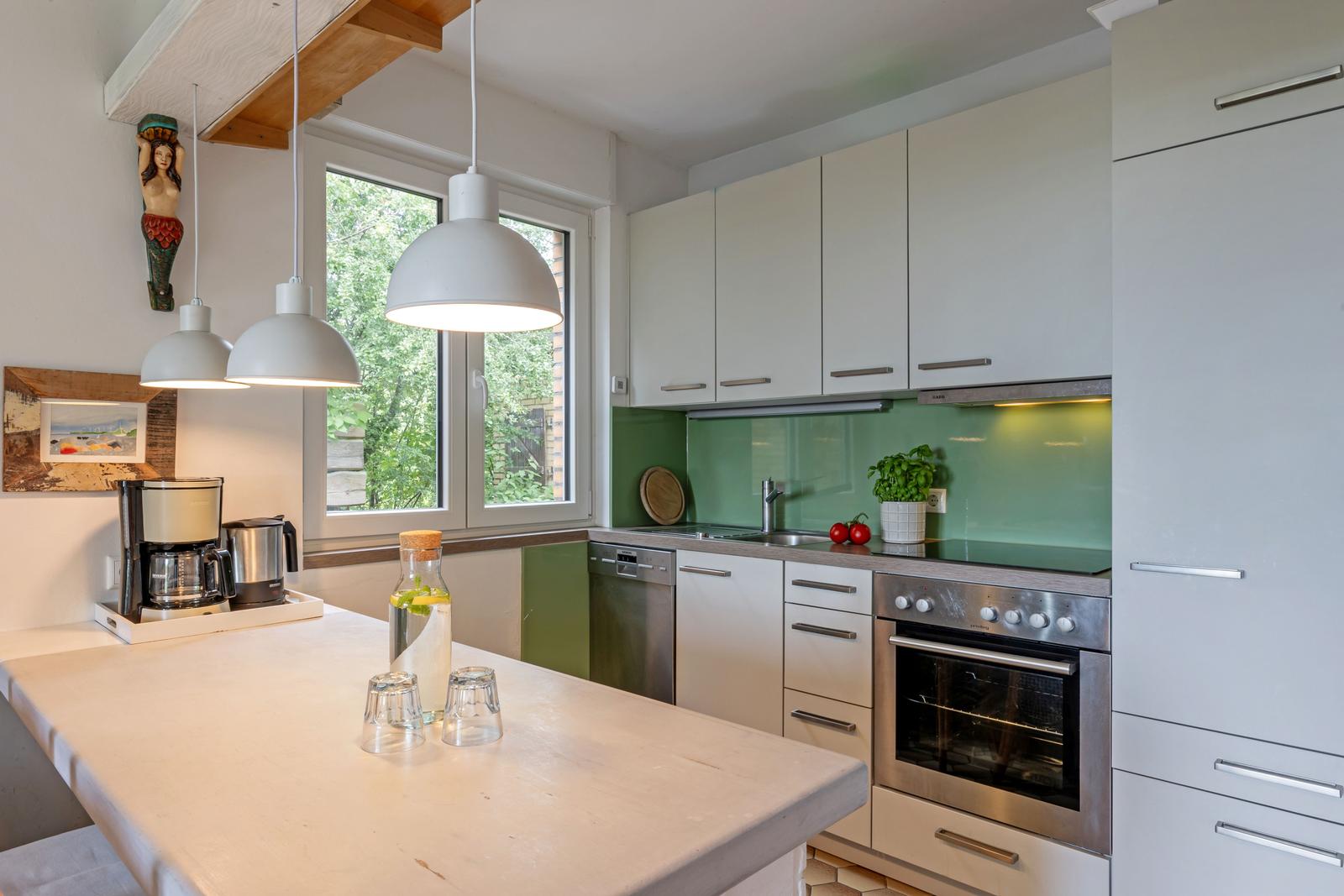 Moderne Küche mit Arbeitsplatte, Kühlschrank, Herd und Fenster.