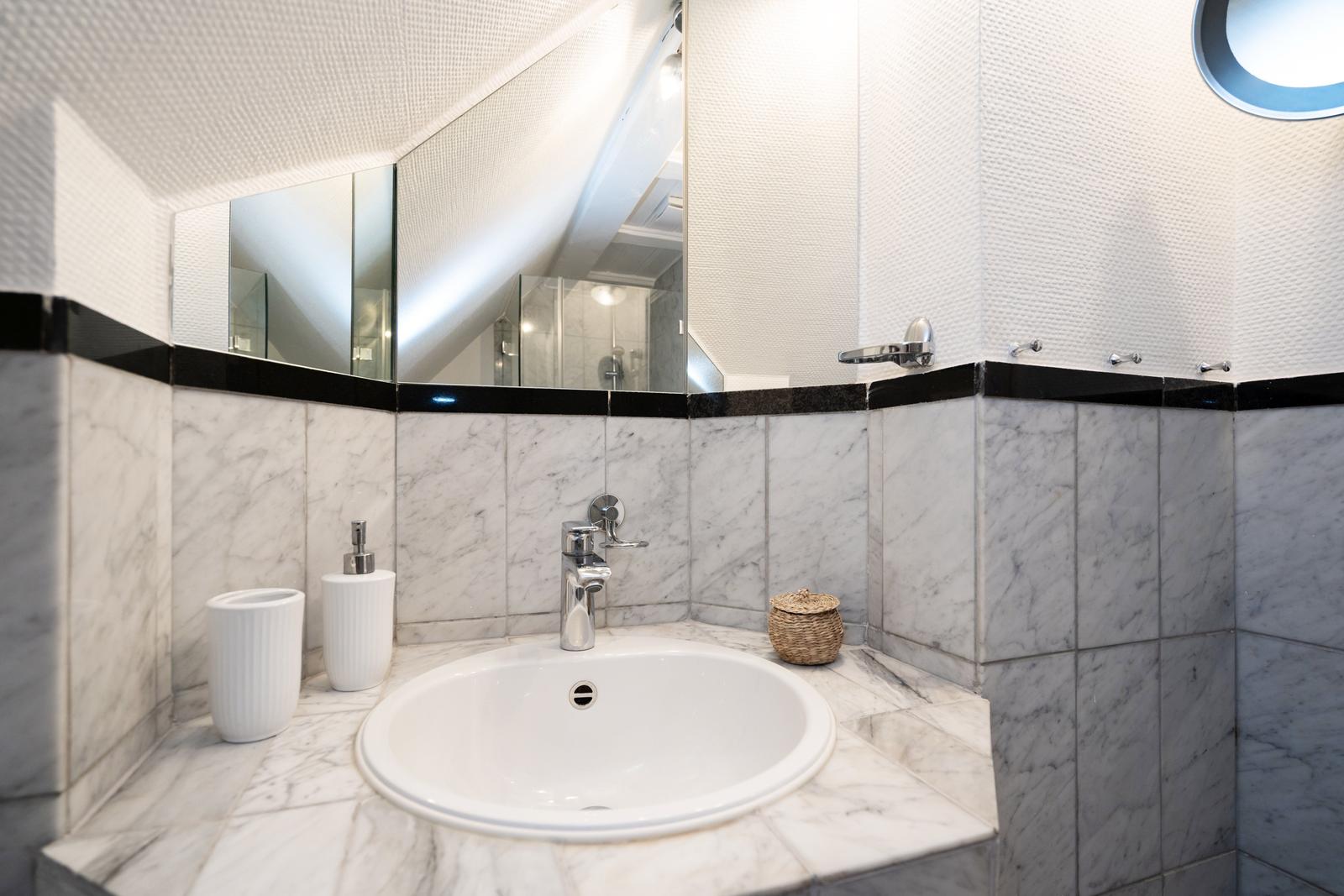 Badezimmer mit Marmorwand, Waschbecken und Spiegel