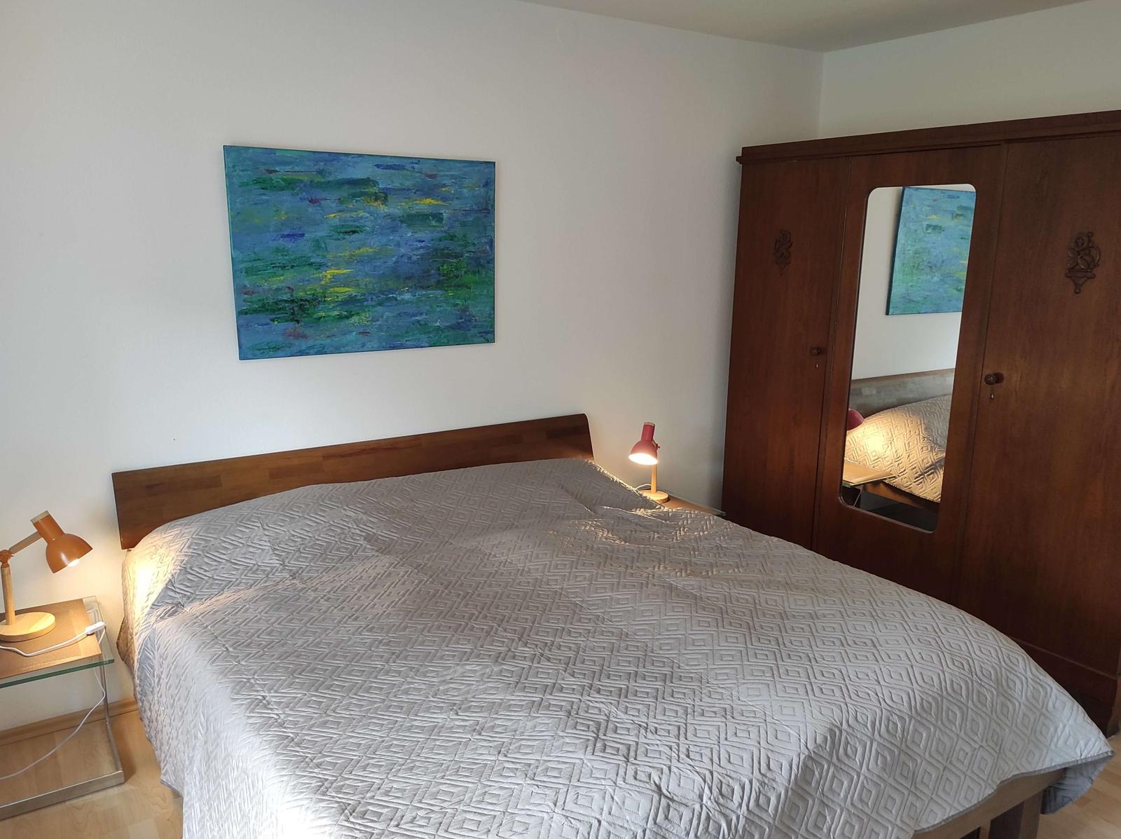 Schlafzimmer mit Bett, Kleiderschrank und Wandbild