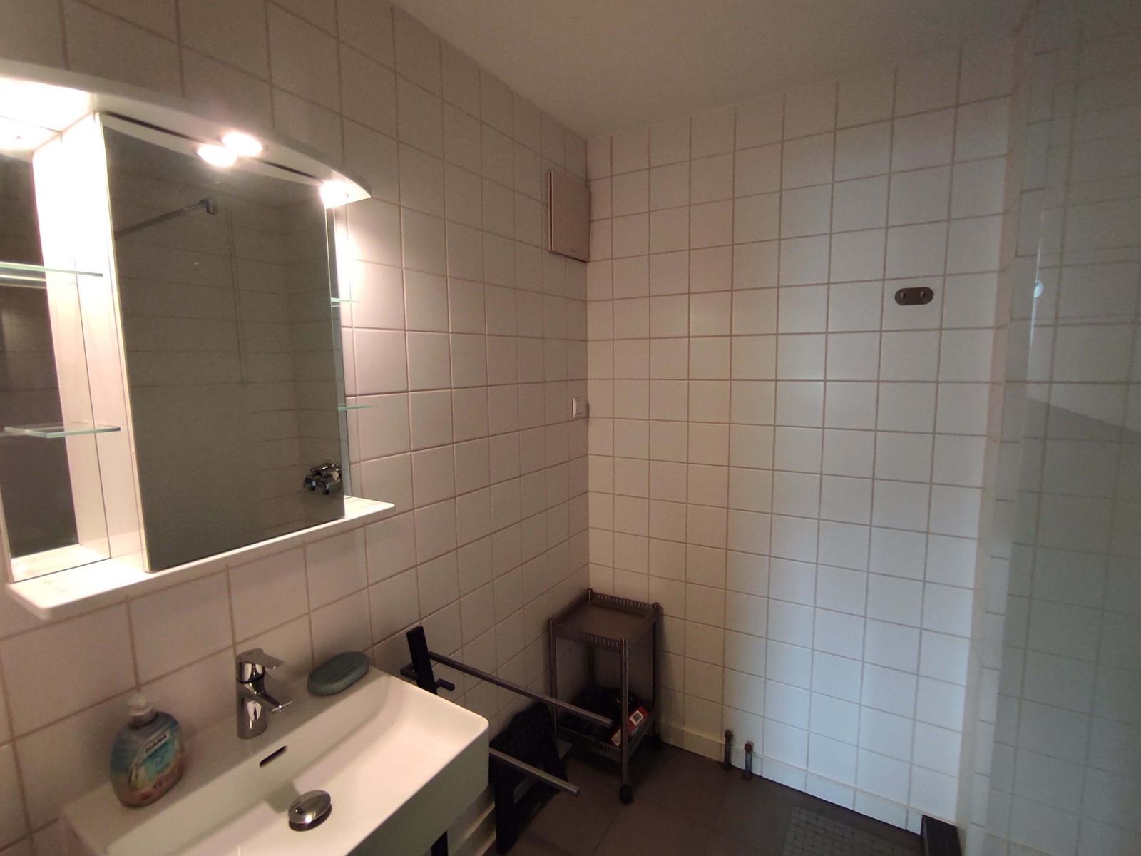 Badezimmer mit Waschbecken, Spiegel und Dusche