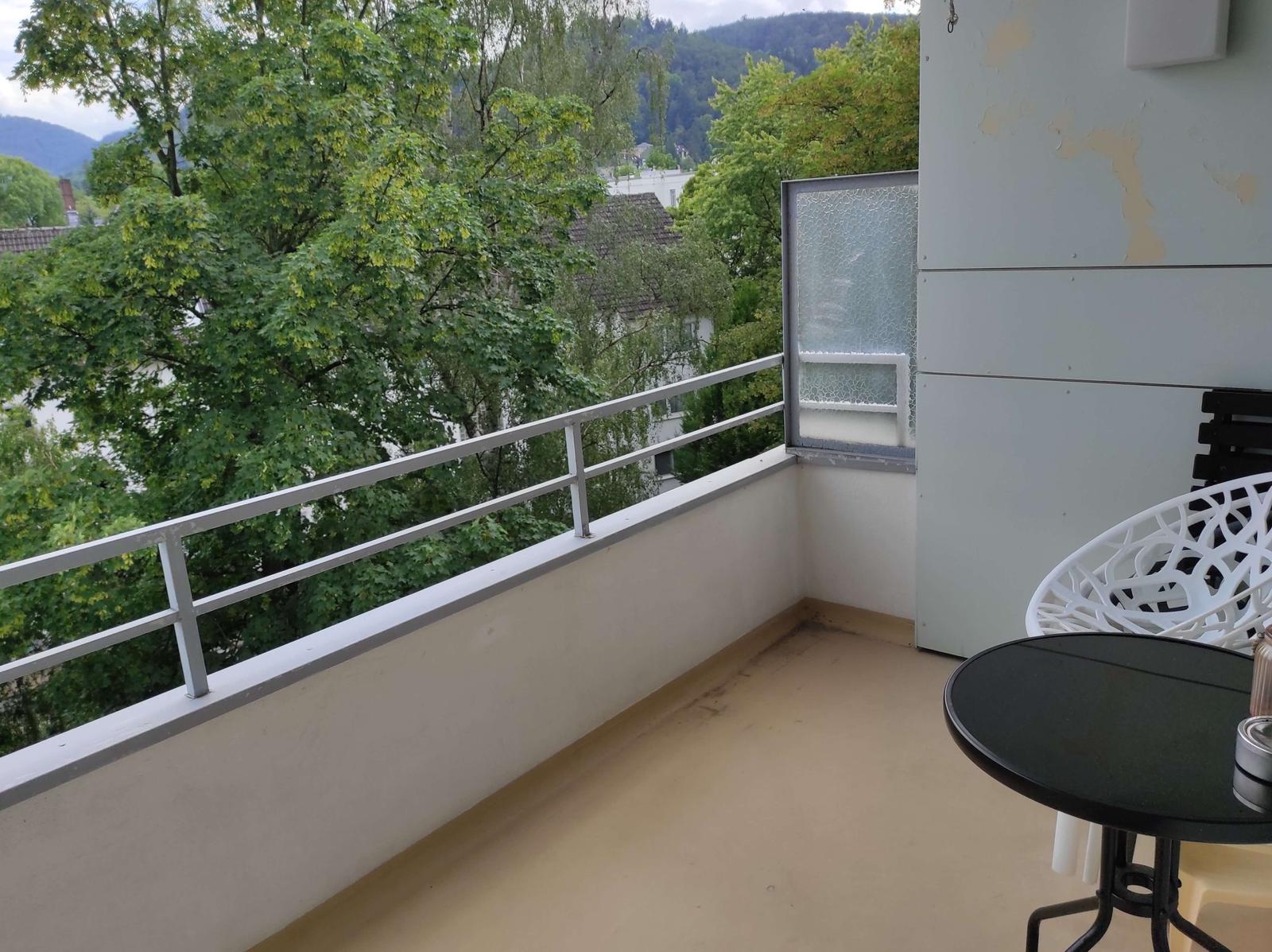 Balkon mit Tisch und Stuhl, Blick auf Bäume und Berge