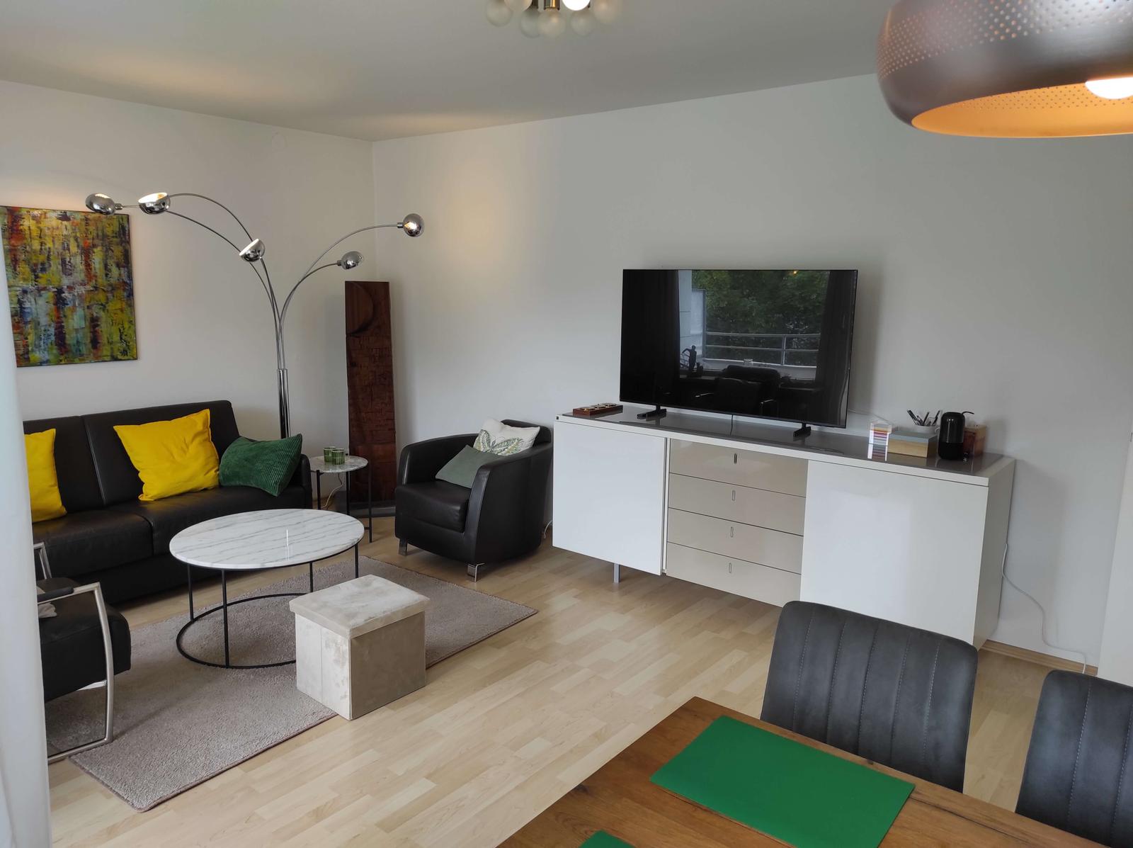 Wohnzimmer mit Sofa, Fernseher und Esstisch