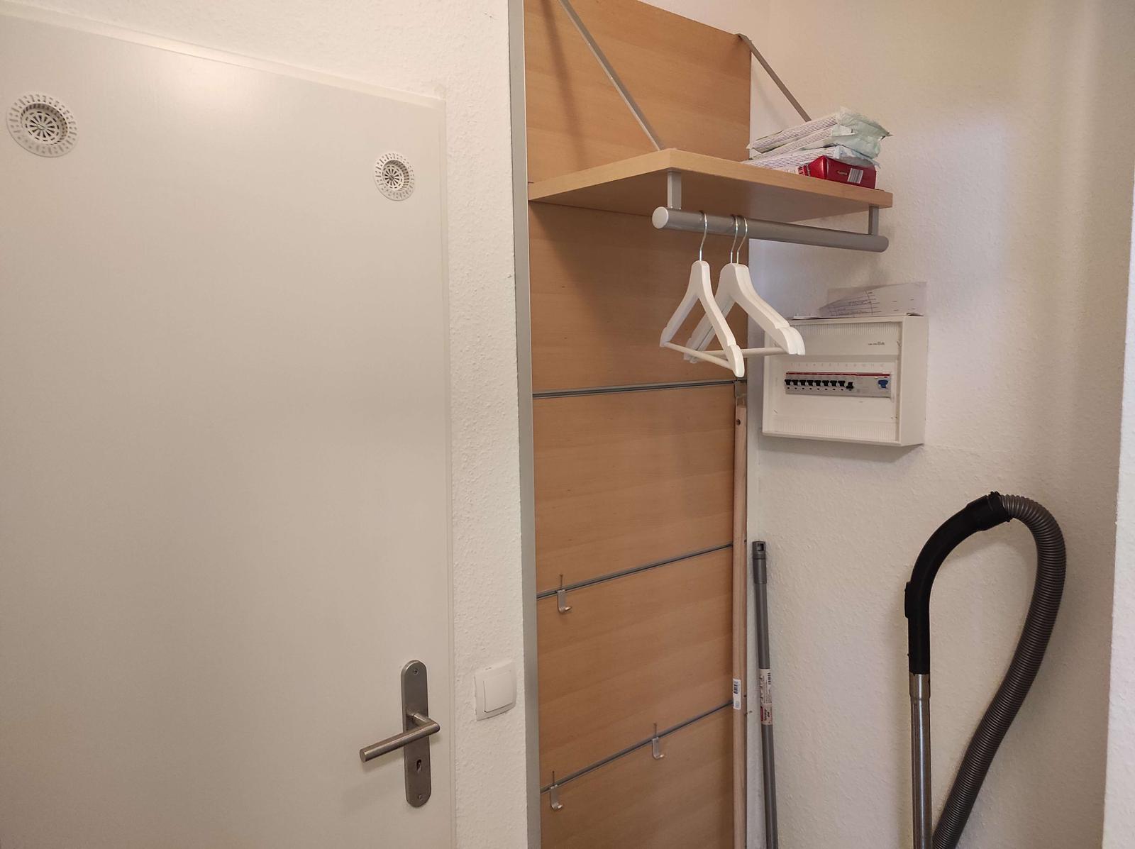 Türe mit Kleiderhaken und Stromverteiler an der Wand