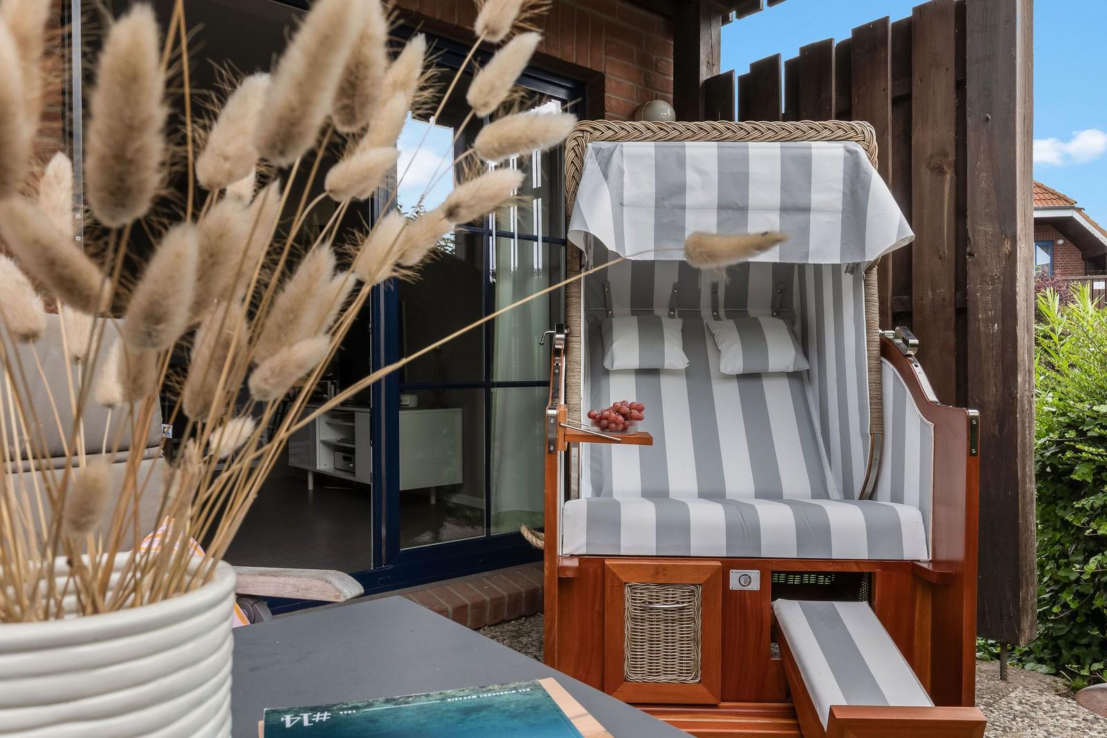 High-quality beach chair with striped cover and cushions on terrace. Background shows glass doors and plants.