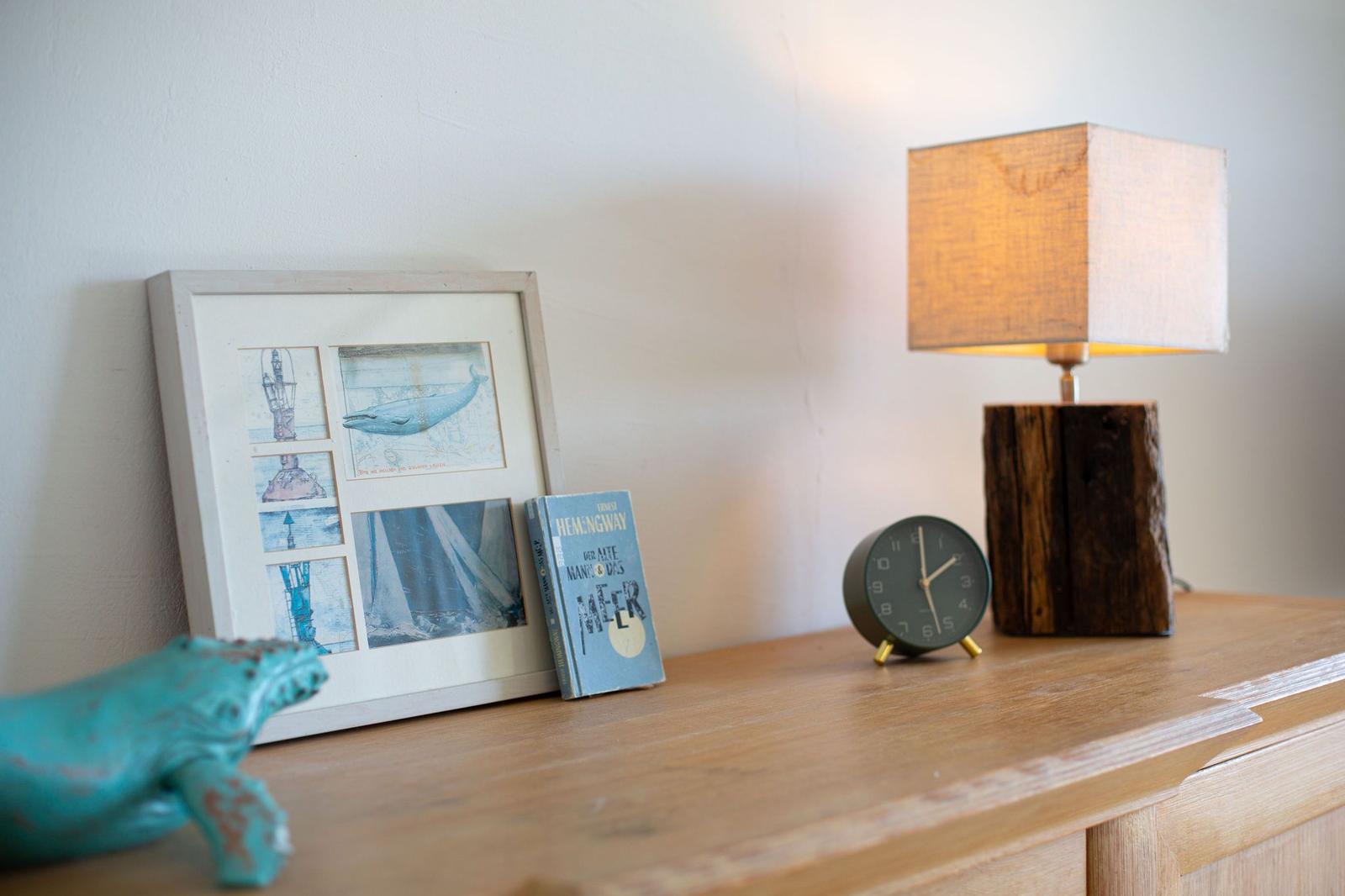 Holzoberfläche mit Bilderrahmen, Buch, Lampe und Wecker.