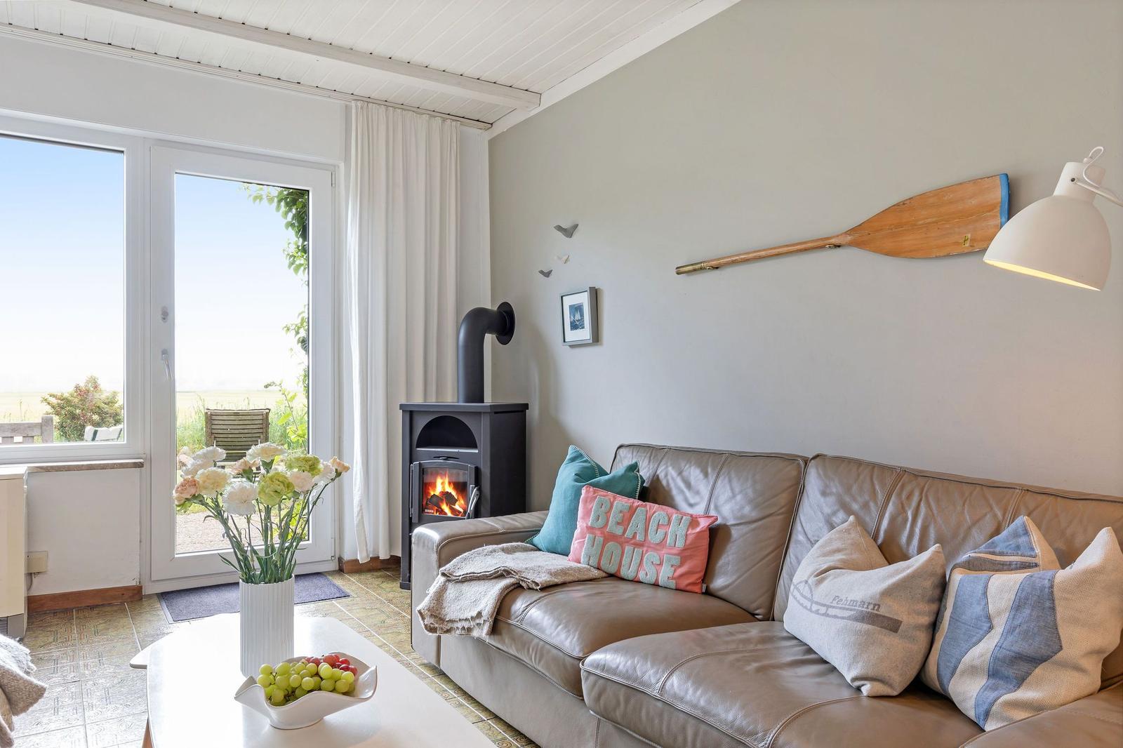 Wohnzimmer mit Sofa, Kamin und Blick auf den Garten.