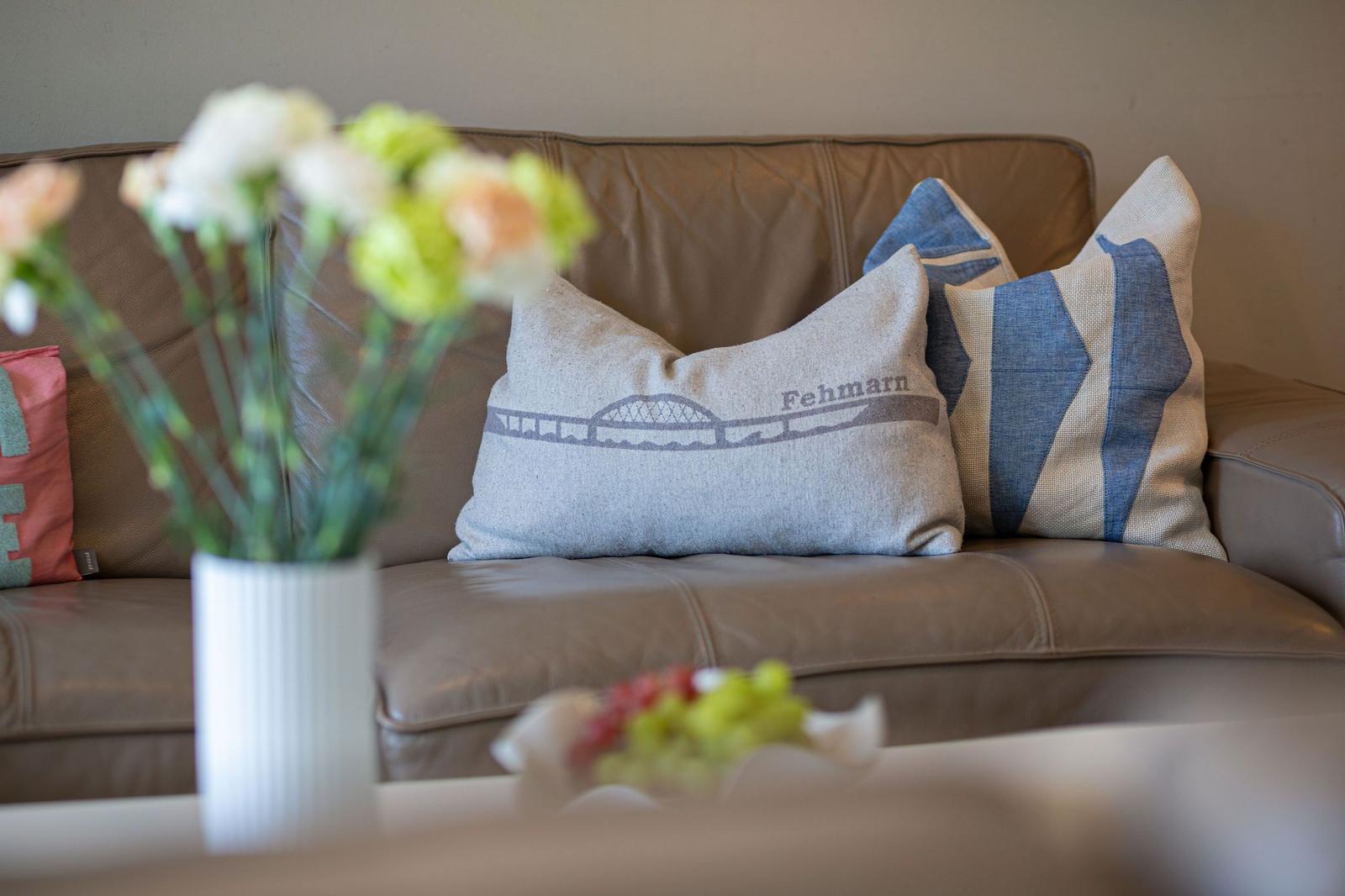 Ein Sofa mit Kissen und Blumen im Vordergrund.