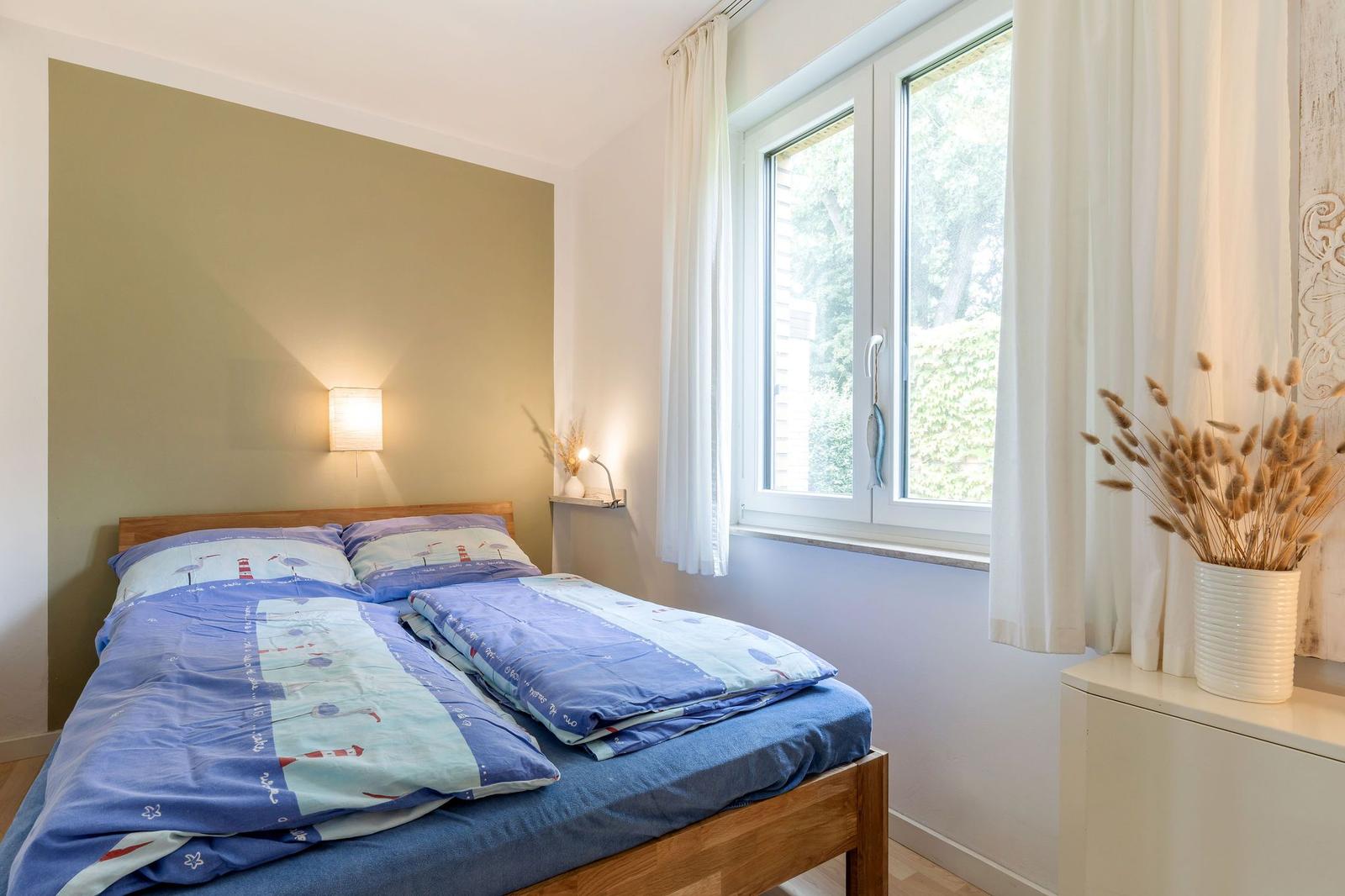 Ein Schlafzimmer mit Doppelbett, Fenster und Nachttisch.