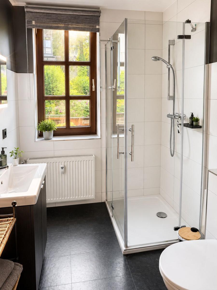 Badezimmer mit Dusche, Waschbecken und Fenster zum Garten.
