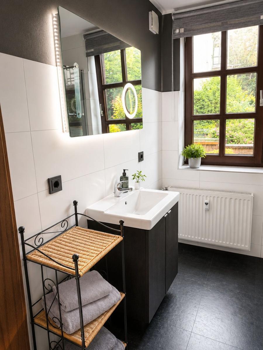 Badezimmer mit Waschbecken, Spiegel, Fenster und Wäscheständer.