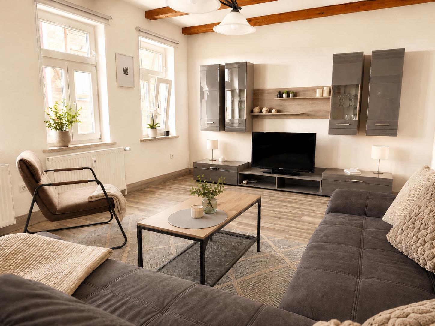 Wohnzimmer mit Sofa, Couchtisch und Fernseher an der Wand.