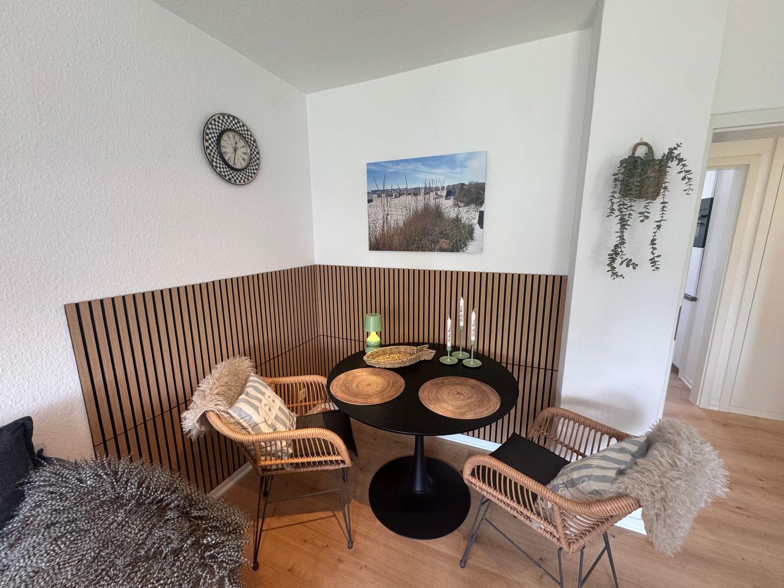 Runder Tisch mit zwei Stühlen, Wandbild und Wanduhr im Ecke.