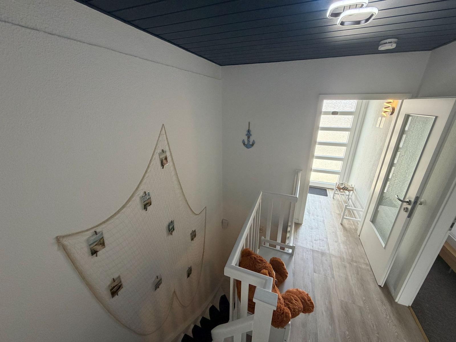 Hausflur mit Treppe, Wanddekoration und Eingangstür.