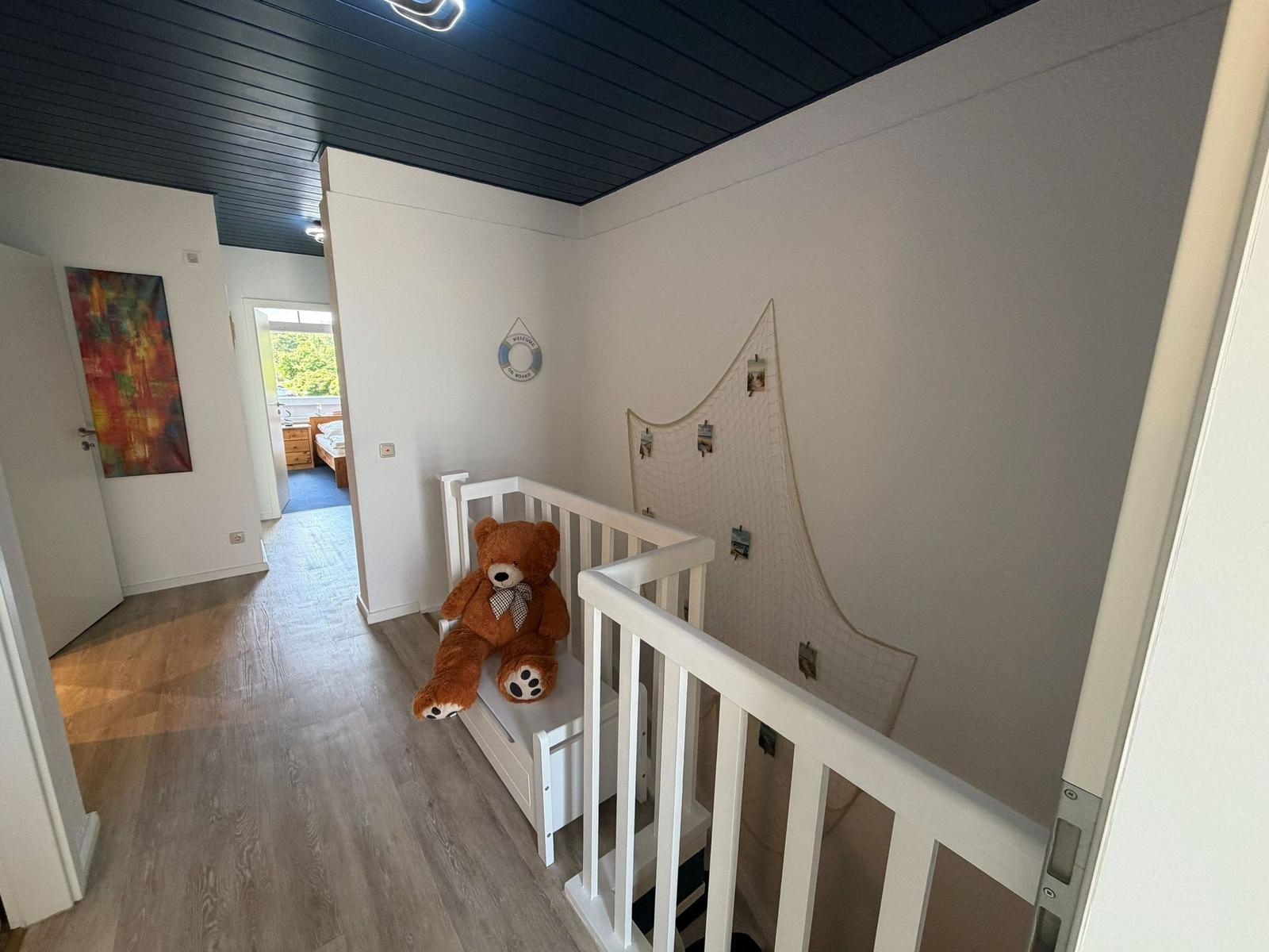Kinderzimmer mit weißem Bett, Plüschbären und Netz an der Wand.