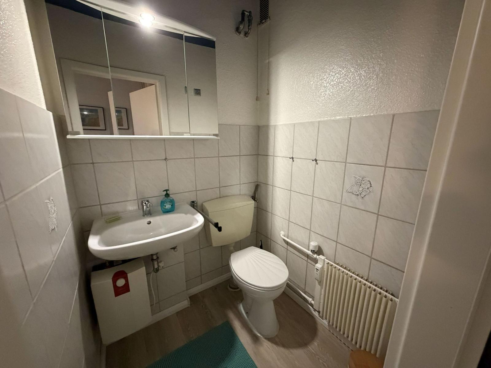 Badezimmer mit Toilette, Waschbecken und Spiegel