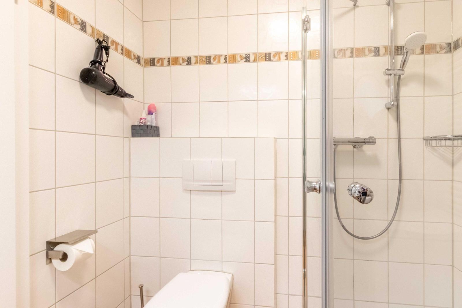 Bathroom with shower, toilet, and towel holder on the wall.