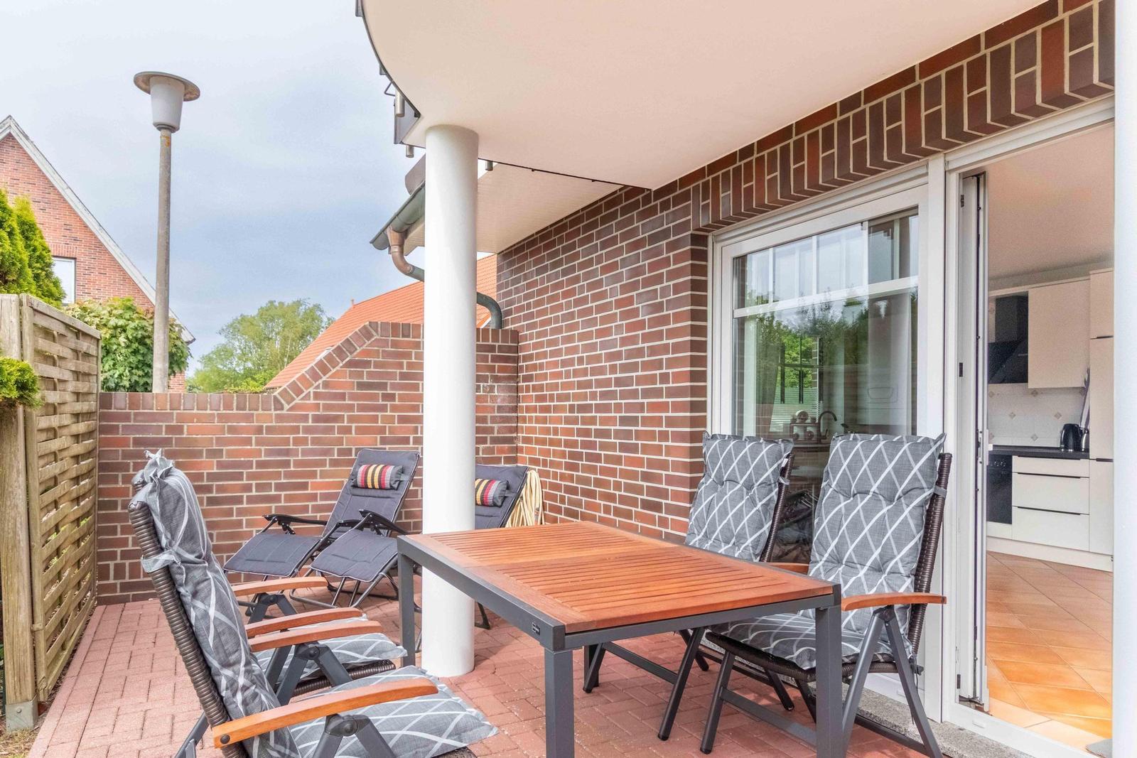 Terrace with table, chairs, and view into kitchen.