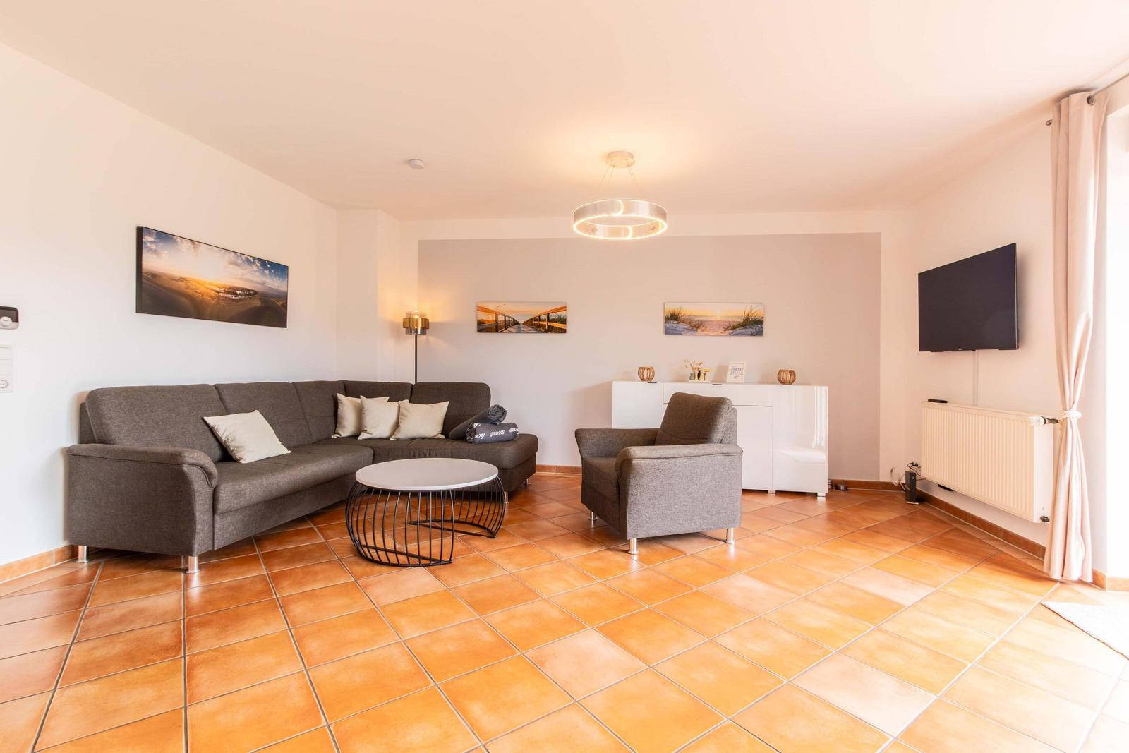Living room with sofa, armchair, coffee table, and TV mounted on the wall.