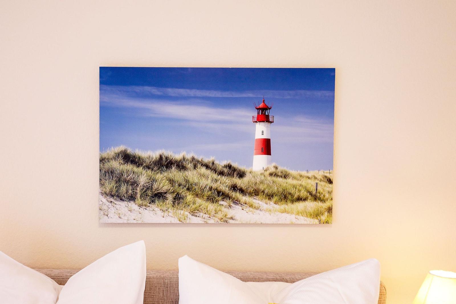 Wandbild mit Leuchtturm auf Dünen unter blauem Himmel