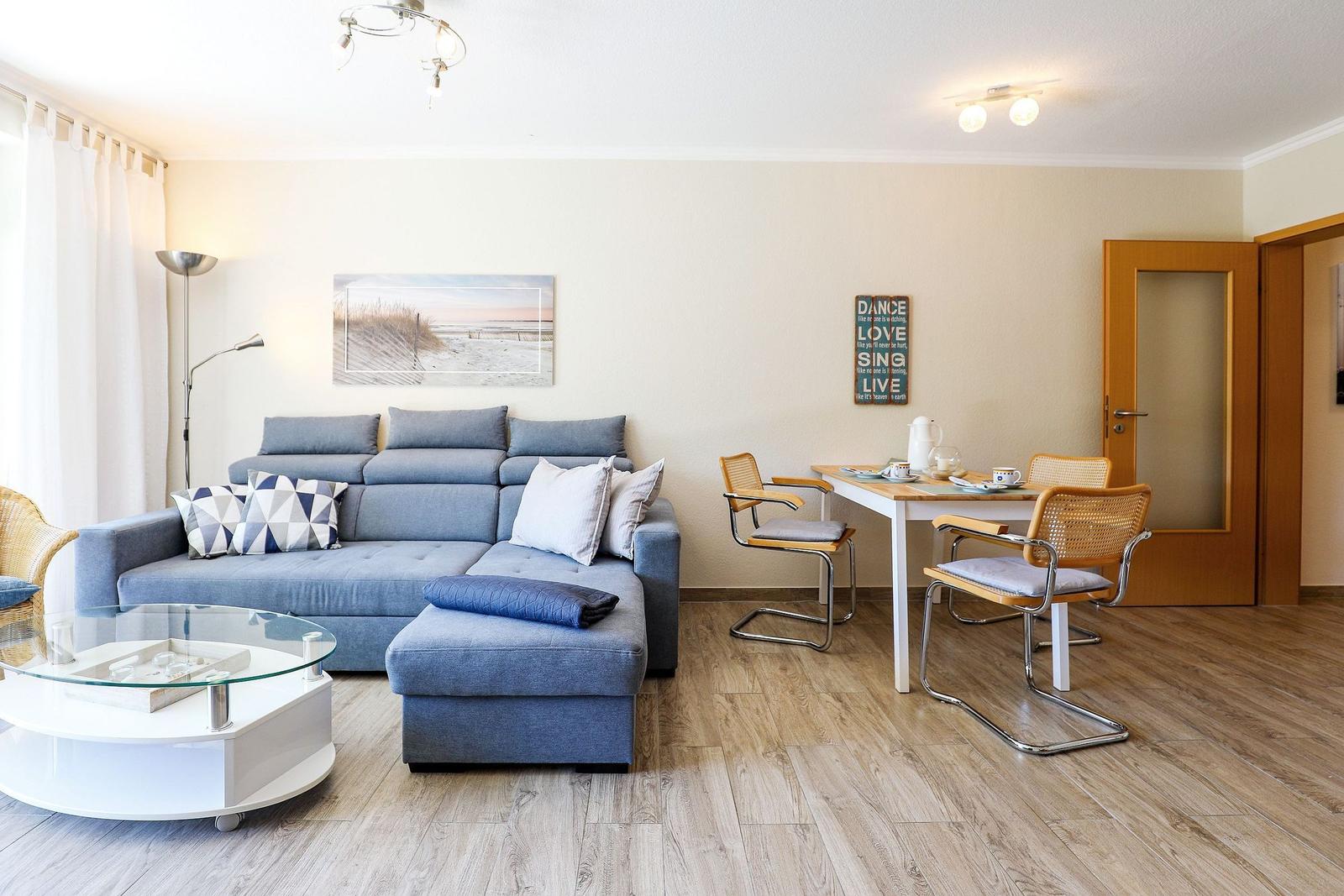 Wohnzimmer mit Sofa, Esstisch und Holzboden. Wandbild und Dekoration.